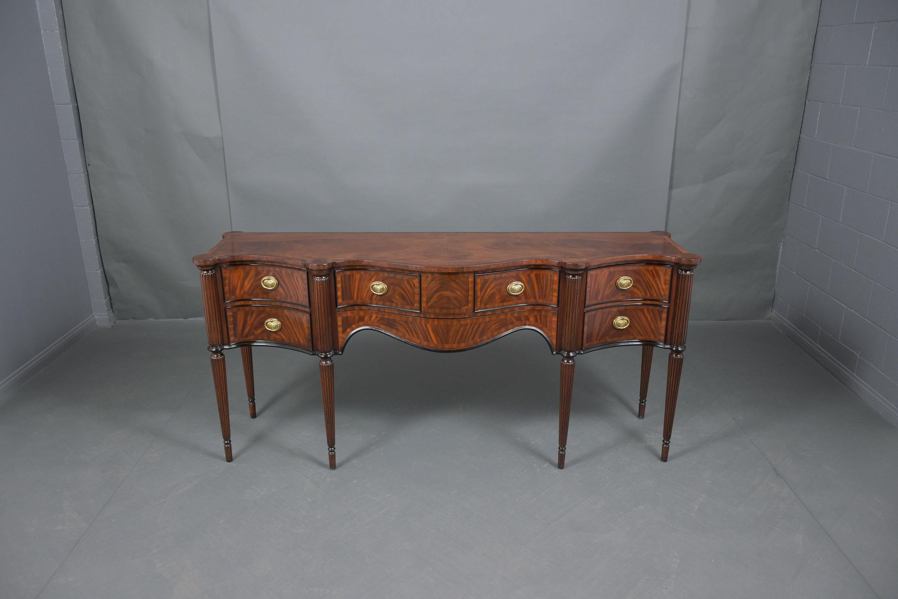 This English George III style server hand-crafted out of flemish mahogany wood features mahogany and ebonized molding color accents with a newly lacquered finish and has been professionally restored by our team of expert craftsmen. The buffet comes
