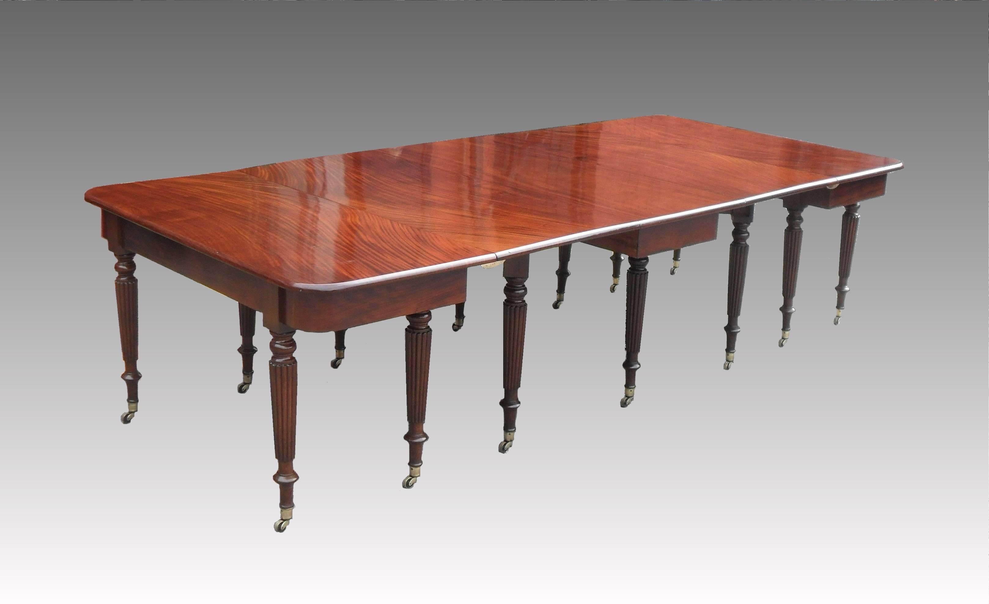 An outstanding quality George IV multifunctional figured mahogany three sectional extending dining table stood on fourteen finely turned and reeded legs with original brass cup castors. The table has a beautiful figured solid mahogany bookmatched