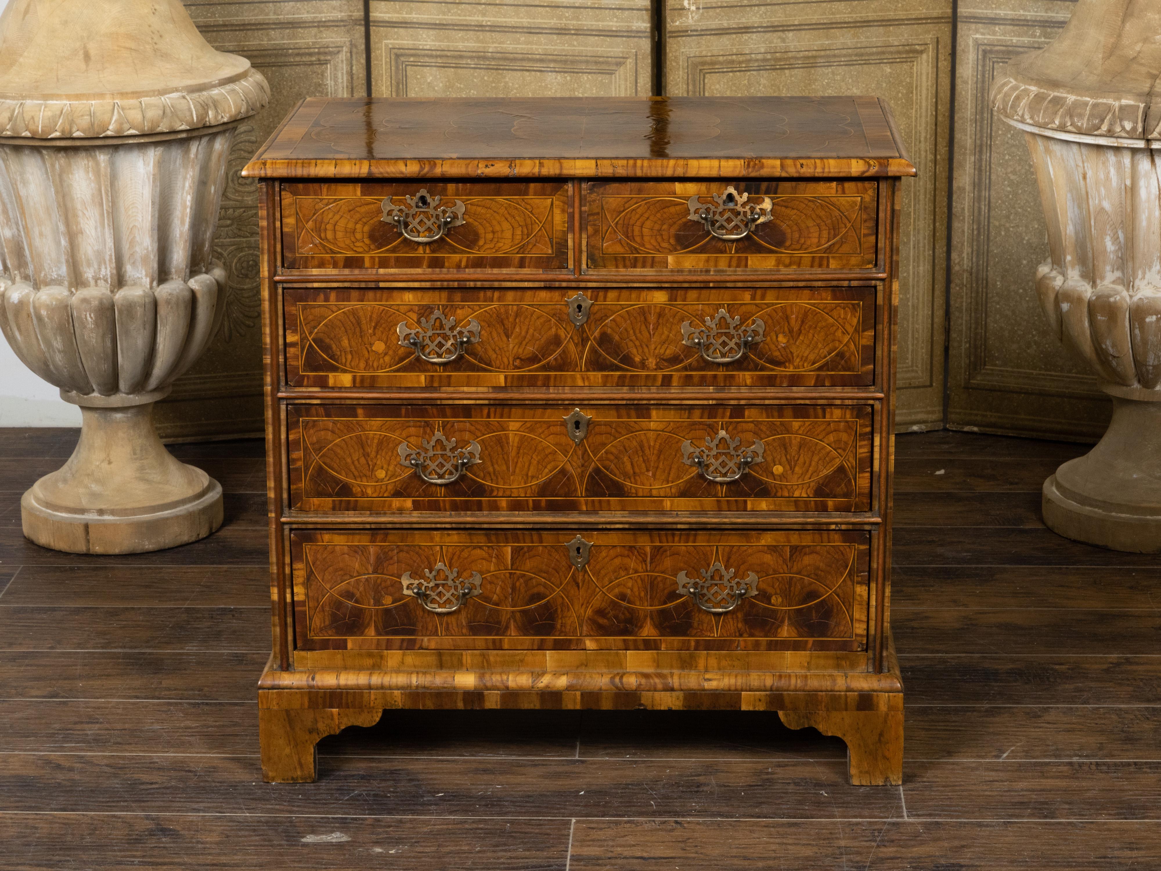 An English Georgian period walnut chest from the early 19th century with oyster veneer, five drawers and Chinese Chippendale style brass hardware. Created in England during the early years of the 19th century, this chest captures the attention with