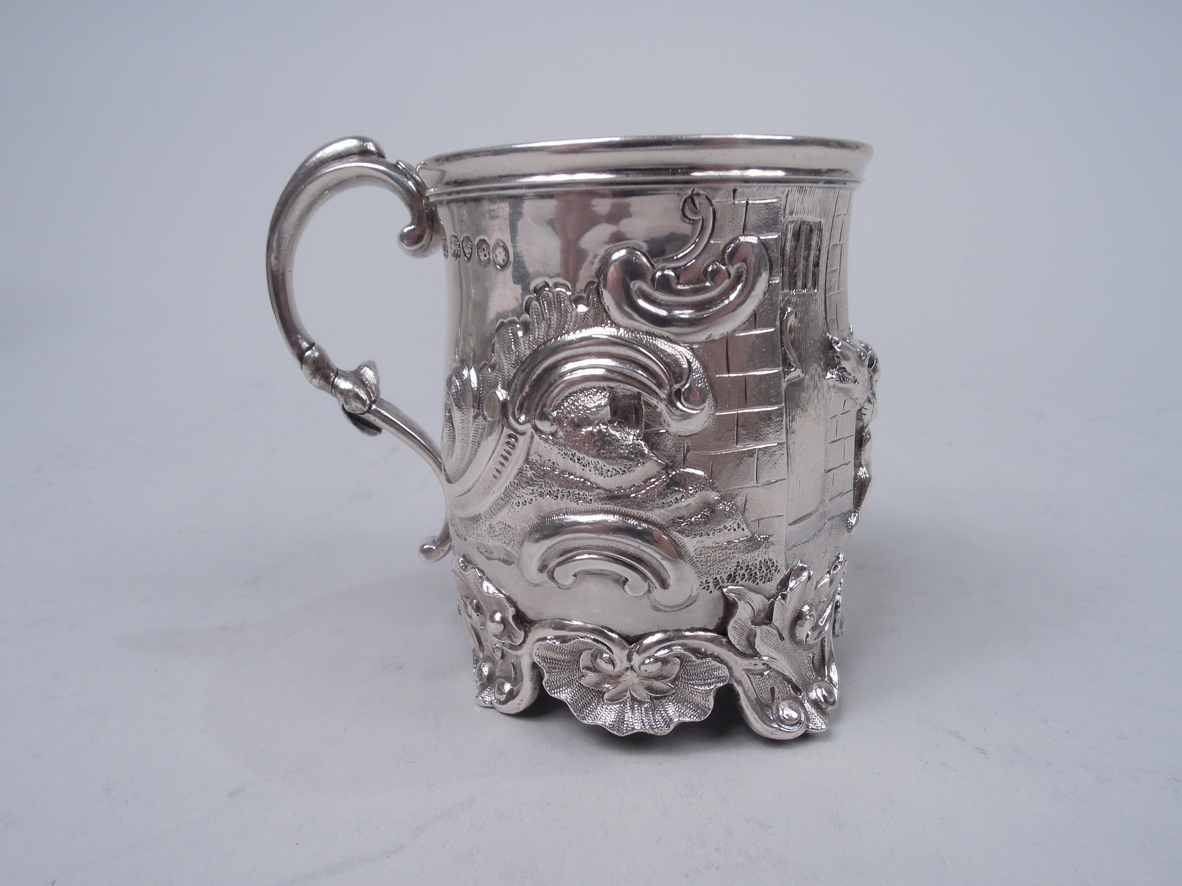 English Georgian sterling silver baby cup, 1837. Bowl has curved sides and scrolled foot rim with applied scallop shells and four leaf and shell supports; leaf-capped double-scroll handle. Gilt interior. Chased and engraved scene of boy riding on