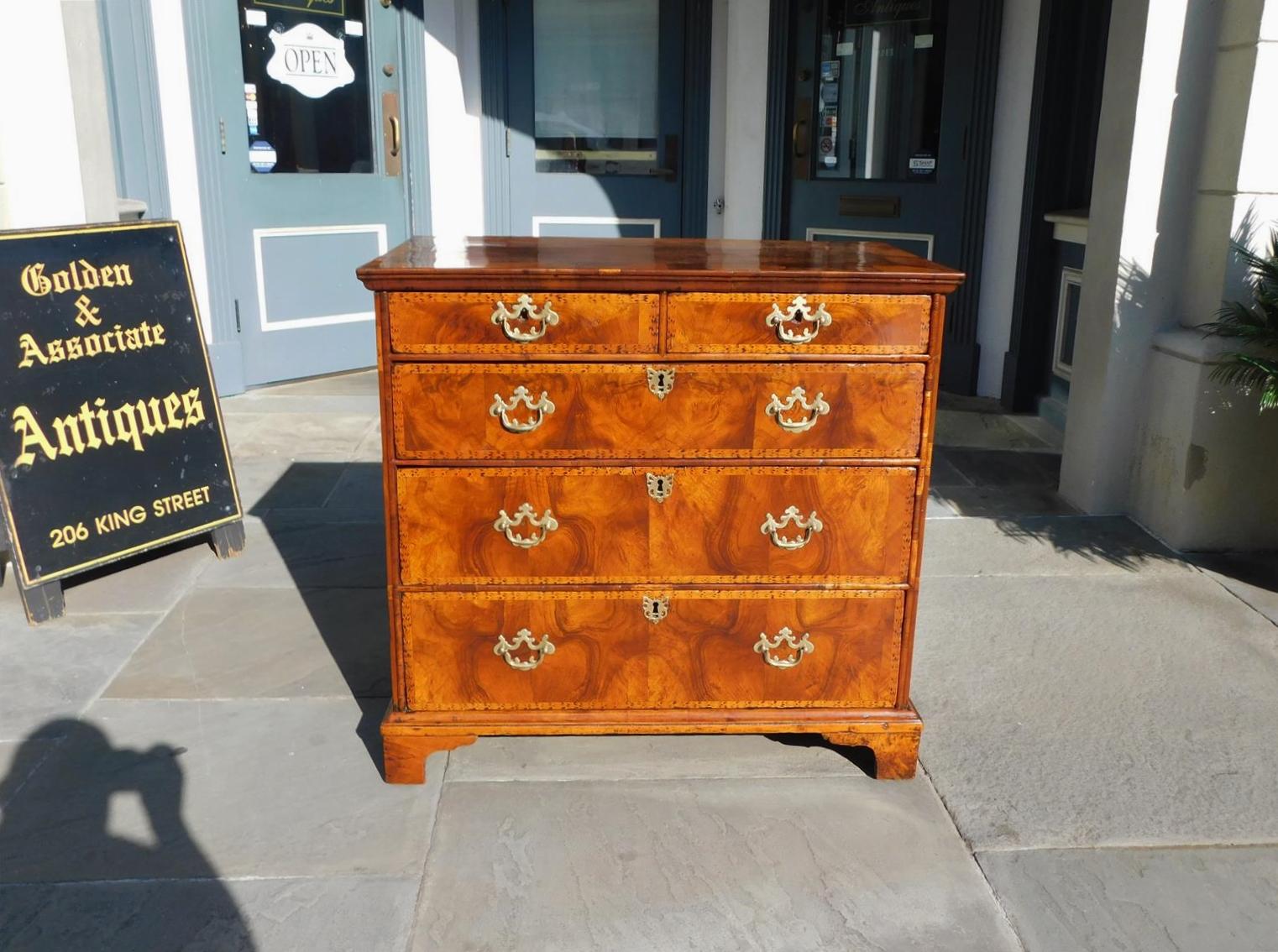 English Georgian rectangular book matched burl walnut graduated chest of drawers with satinwood feather bandings and ebony checkered inlays, period foliate brasses with escutcheons, and resting on the original bracket feet. Mid 18th century.
