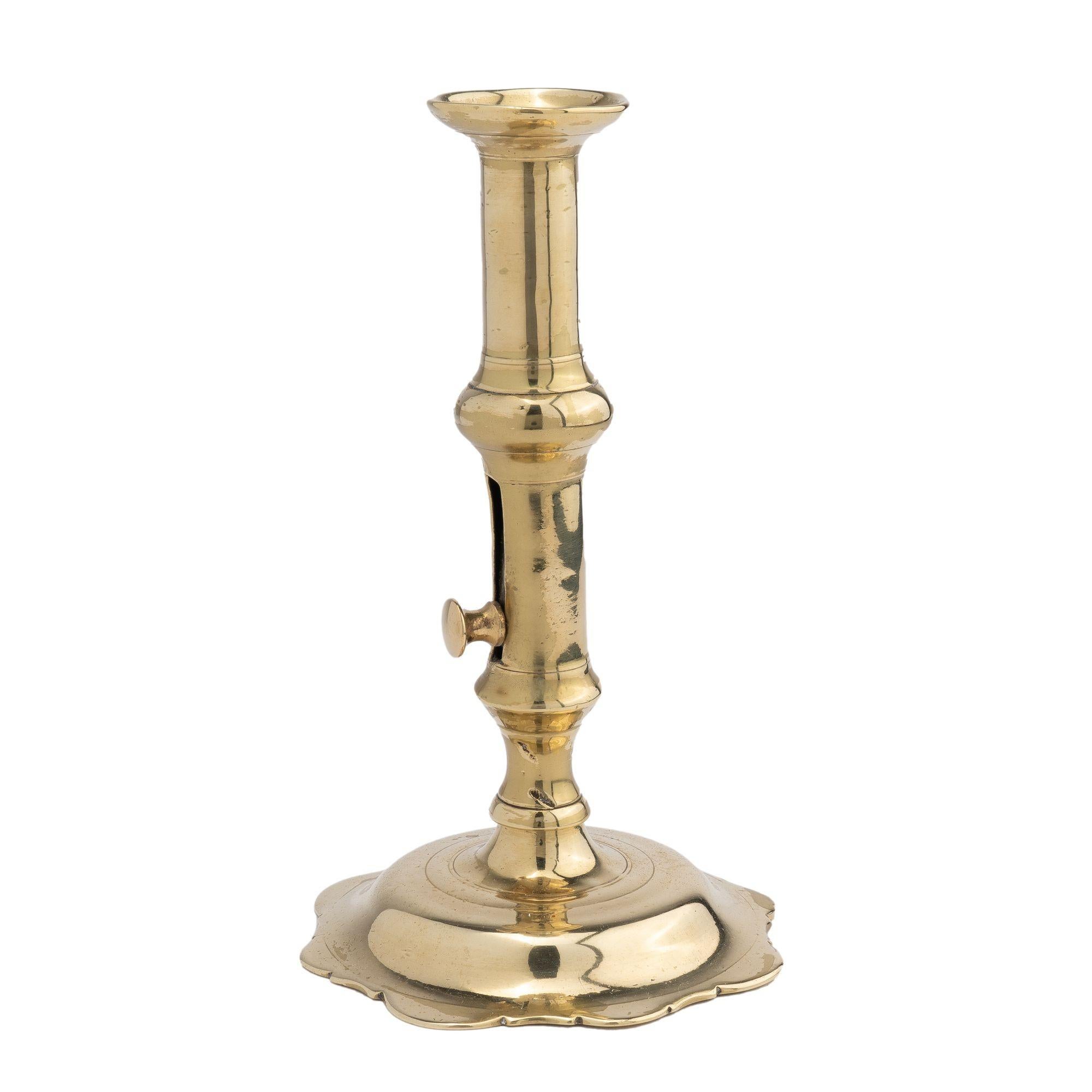 English Georgian hollow core cast brass Queen Anne canon barrel form candlestick. The design features a cupped bobeshe, scolloped base, and side mounted knob candle ejector.

Birmingham, England, circa 1760.
