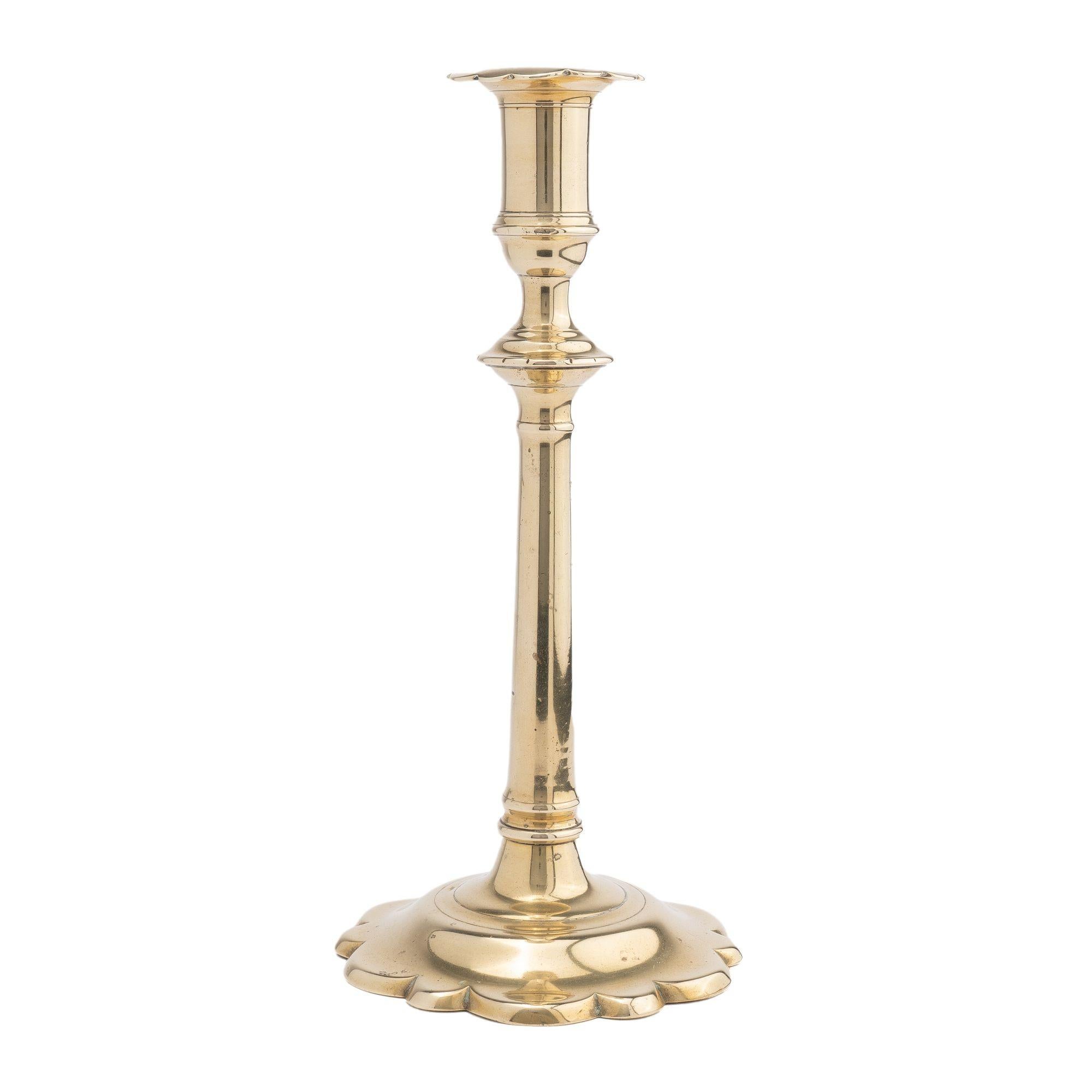 Cast brass Georgian candlestick with scolloped base and matching scolloped edge bobesh.

England, circa 1770.