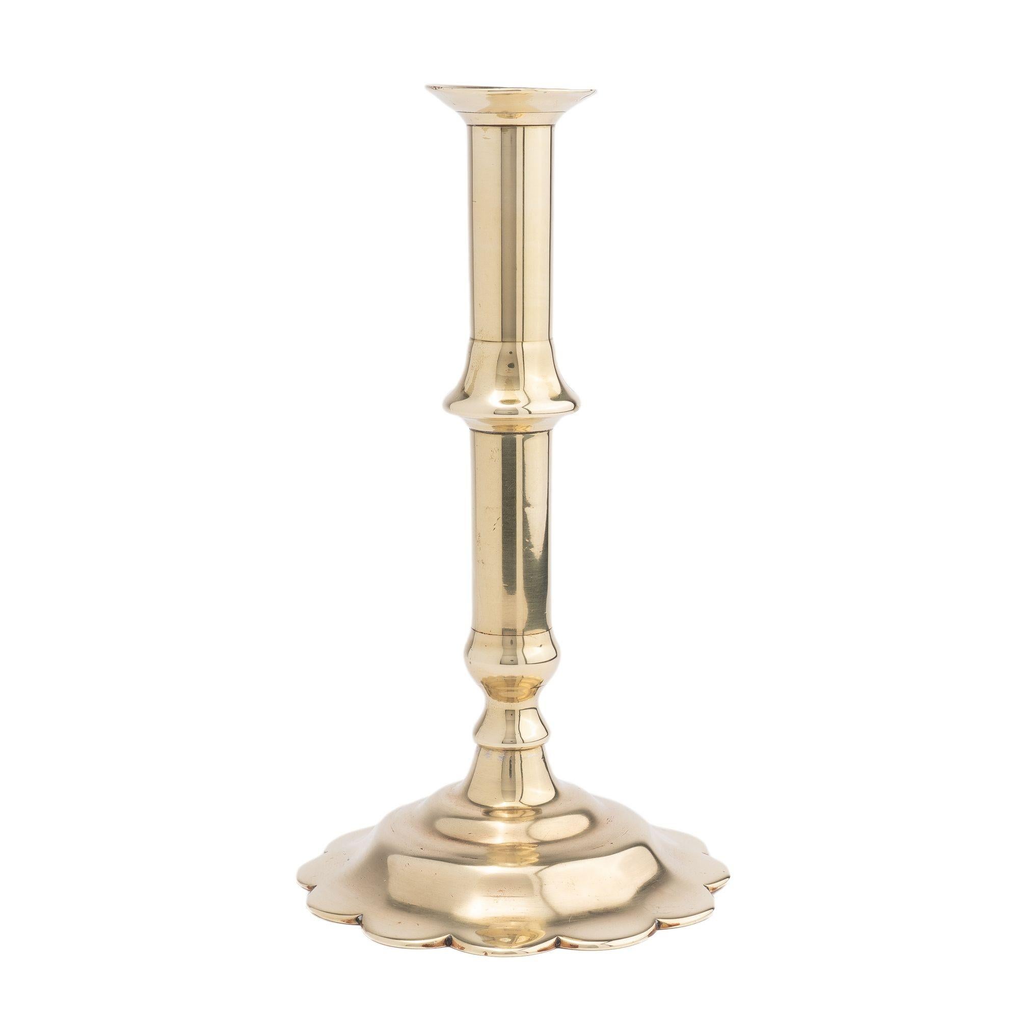 English Georgian cast brass Queen Anne cannon barrel shaft candlestick, with push up candle ejector, peened to a petal base.

Birmingham, England, circa 1760.