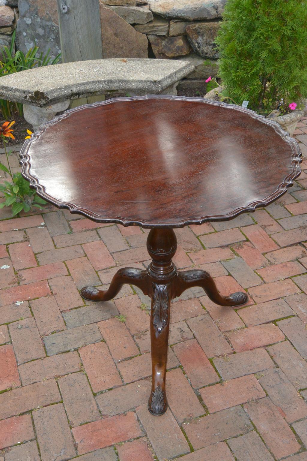 English Georgian Chippendale period plum pudding mahoganypiecrust tilt and turn table. This tea table is beautifully carved with the top being a single board, the pedestal base having carving to the stem as well as sophisticated acanthus leaf