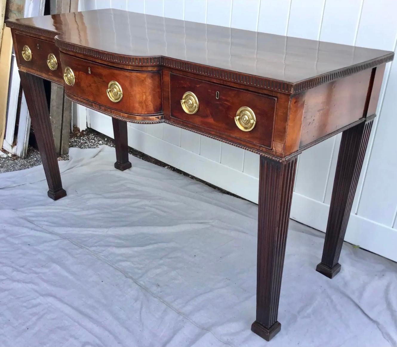 English Georgian Chippendale mahogany server. Center bow front top with three drawers, fluted trim, center bowfront drawer flanked by single drawer either side, brass pulls, fluted tapered legs. Wonderful old mellow patina.