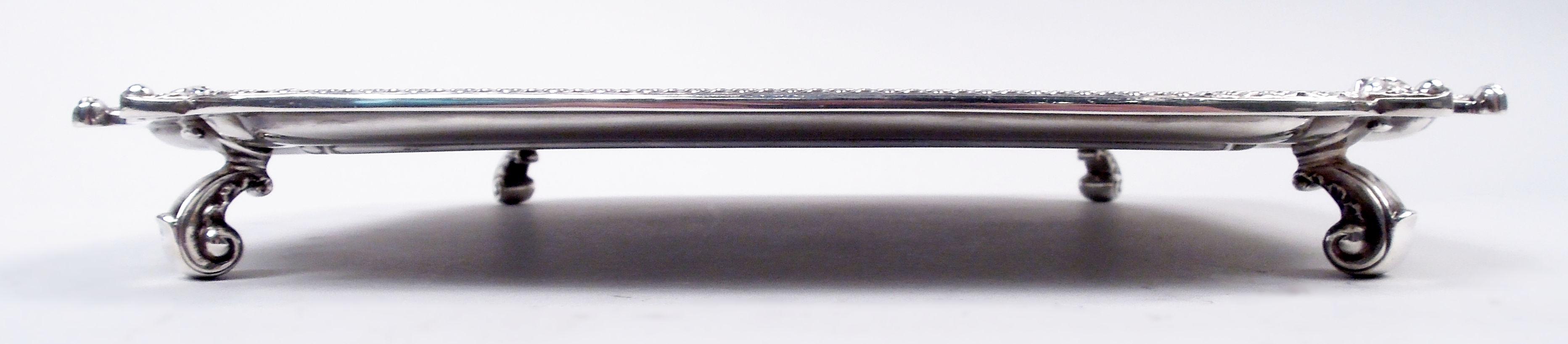 English Georgian Classical sterling silver salver, 1954. Square cartouche; curvilinear concave corners with applied scallop shells and rosette rim. Leaf-capped volute-scroll supports at corners. Fully marked including maker’s stamp (Adie Brothers