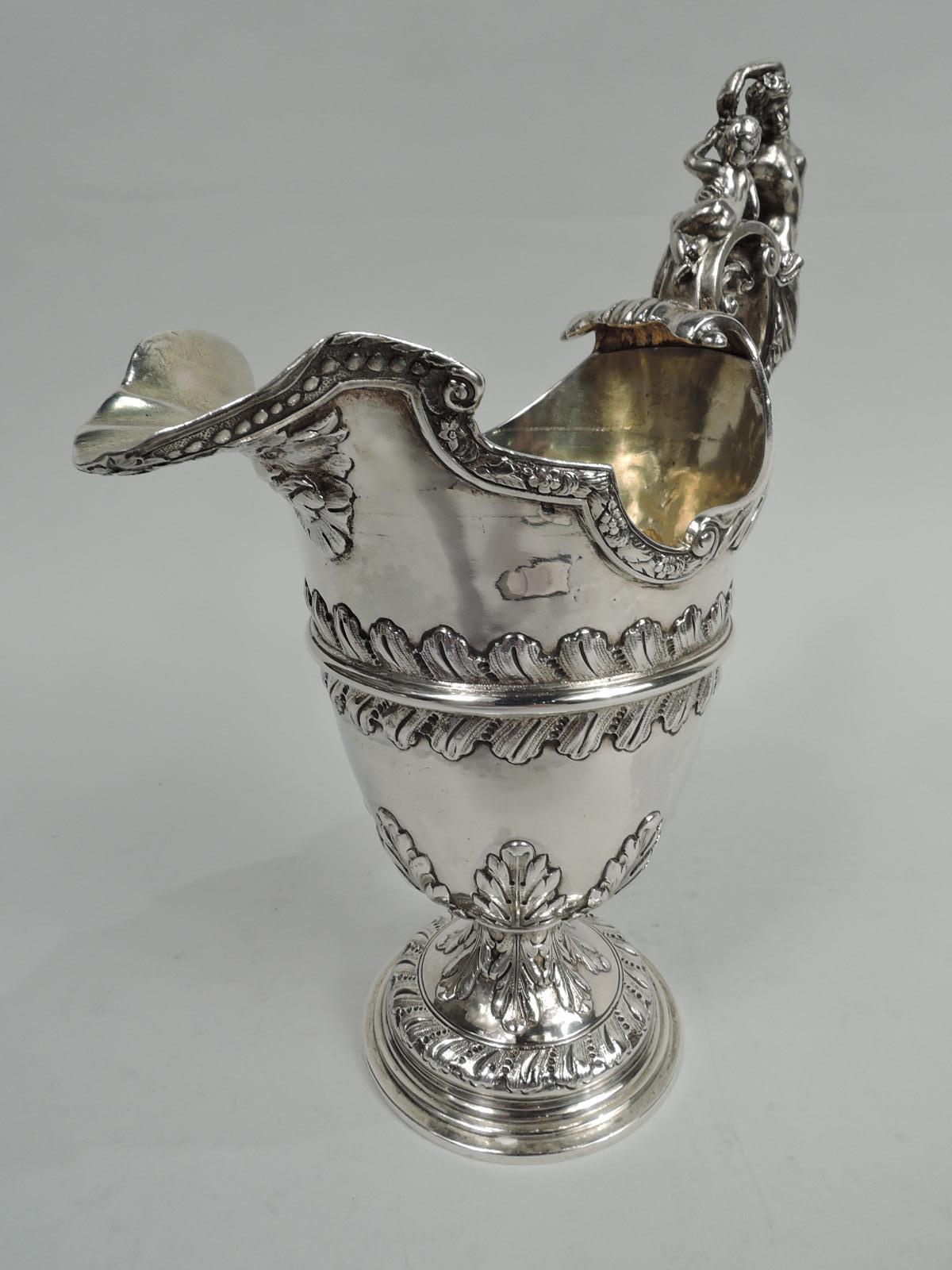 English Georgian Classical sterling silver ewer, 18th century. Girdled ovoid bowl and scrolled helmet mouth with beaded and flowering strapwork rim; cast double-scroll handle with Venus, her torso undraped offering grapes to recumbent Cupid. Satyr