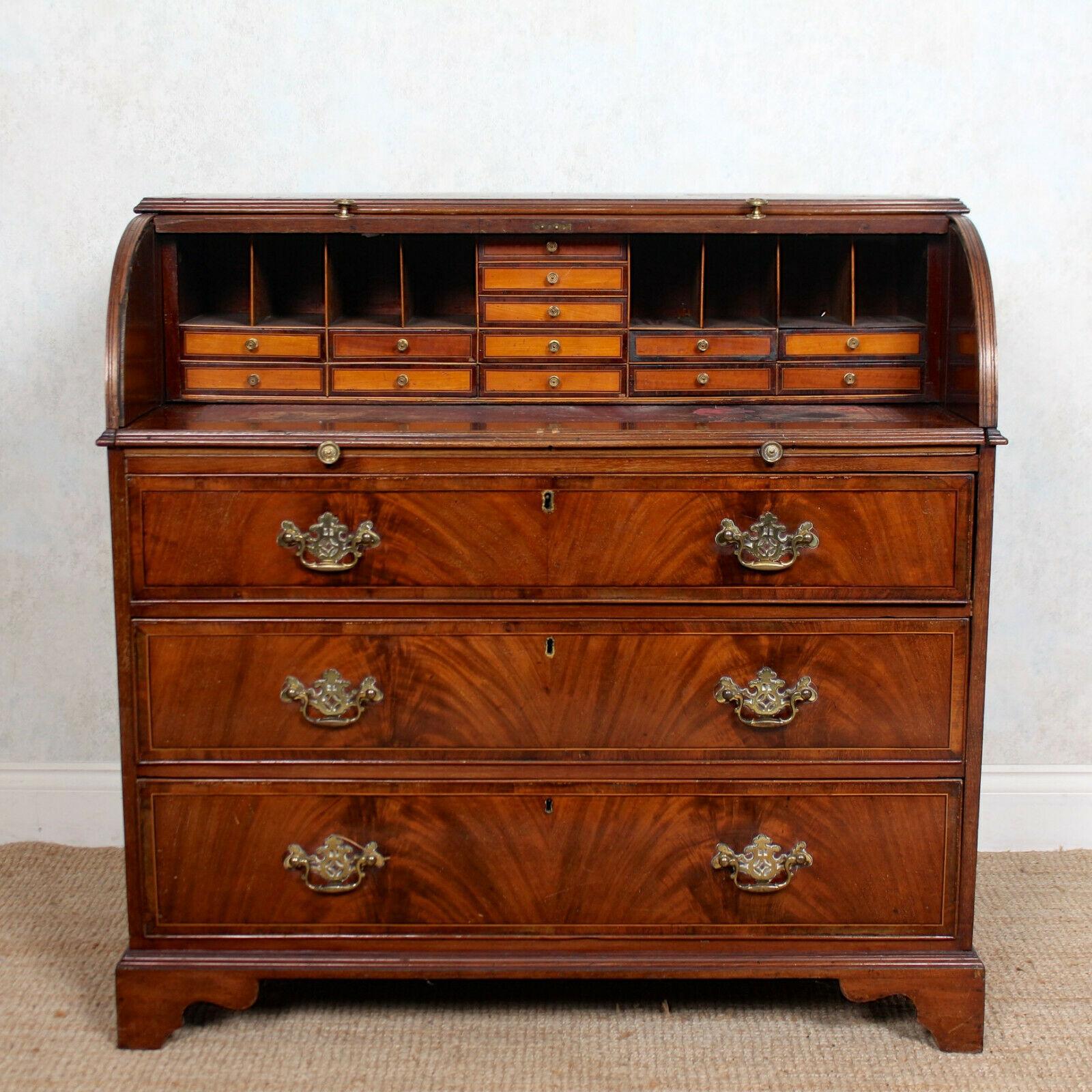 An impressive George IV mahogany cylinder bureau.

The rectangular top with inlaid marquetry panel above a tambour front enclosed a fitted interior comprising tooled leather writing surface, arrangement of drawers and pigeon holes. Fitted three