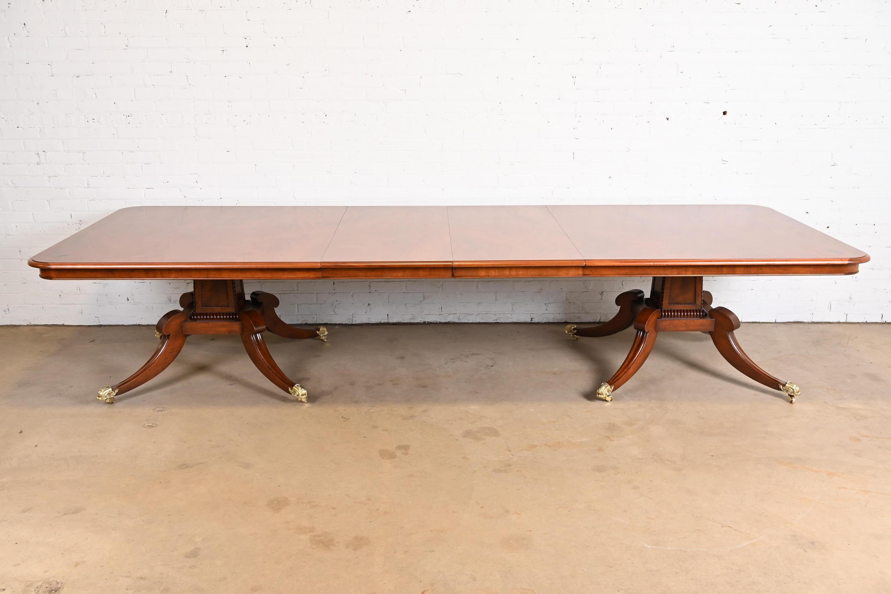An exceptional English Georgian or Regency style double pedestal extension dining table

By Restall Brown & Clennell

England, Circa 1980s

Gorgeous figured mahogany, with ebony inlay, carved solid mahogany pedestals, and brass paw feet and