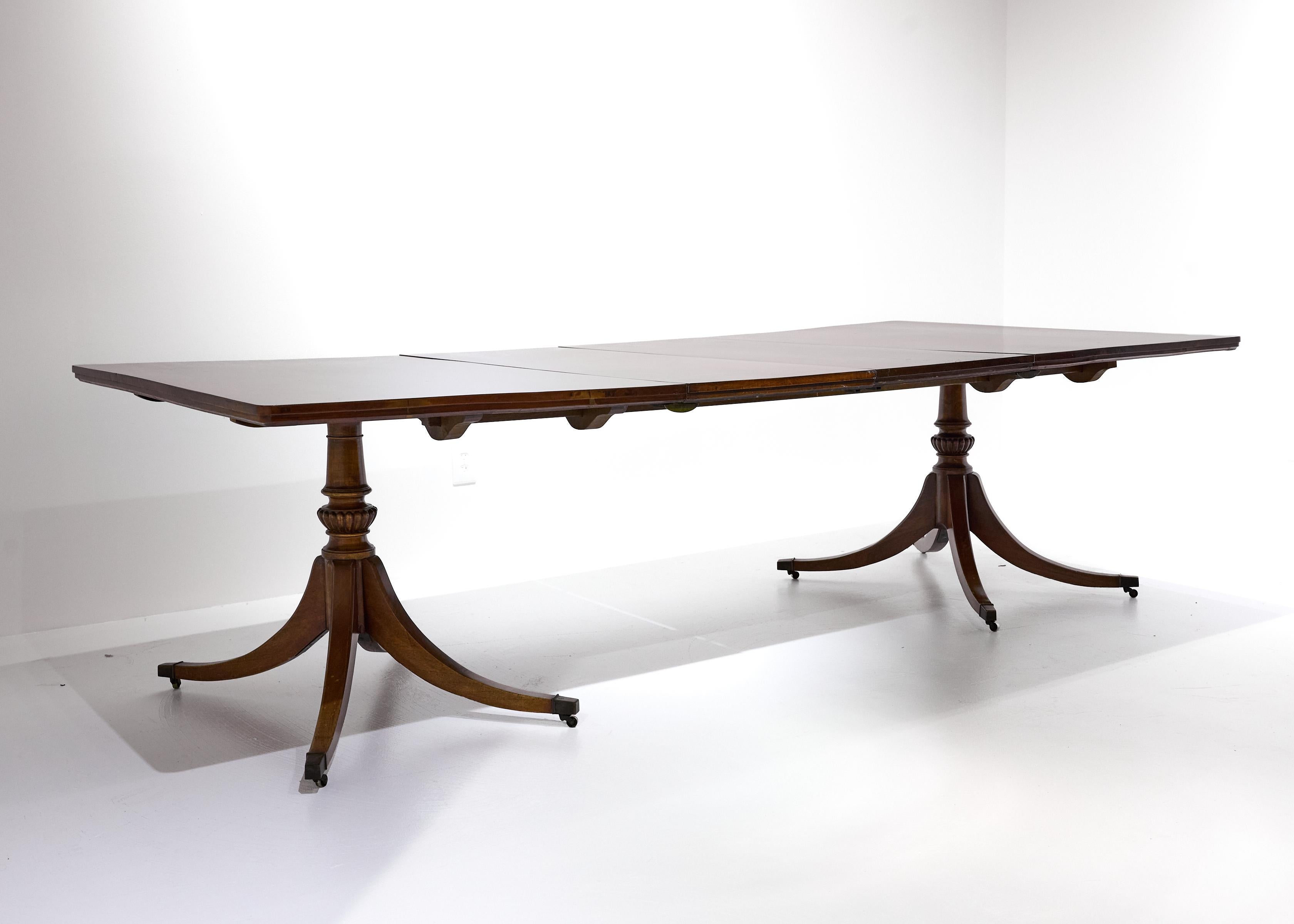 
Table de salle à manger de style géorgien anglais du début du 20e siècle, de belle qualité, en acajou délavé. Le plateau et les feuilles sont en planches d'acajou massif, avec des bords biseautés sur le périmètre. La table est soutenue par deux