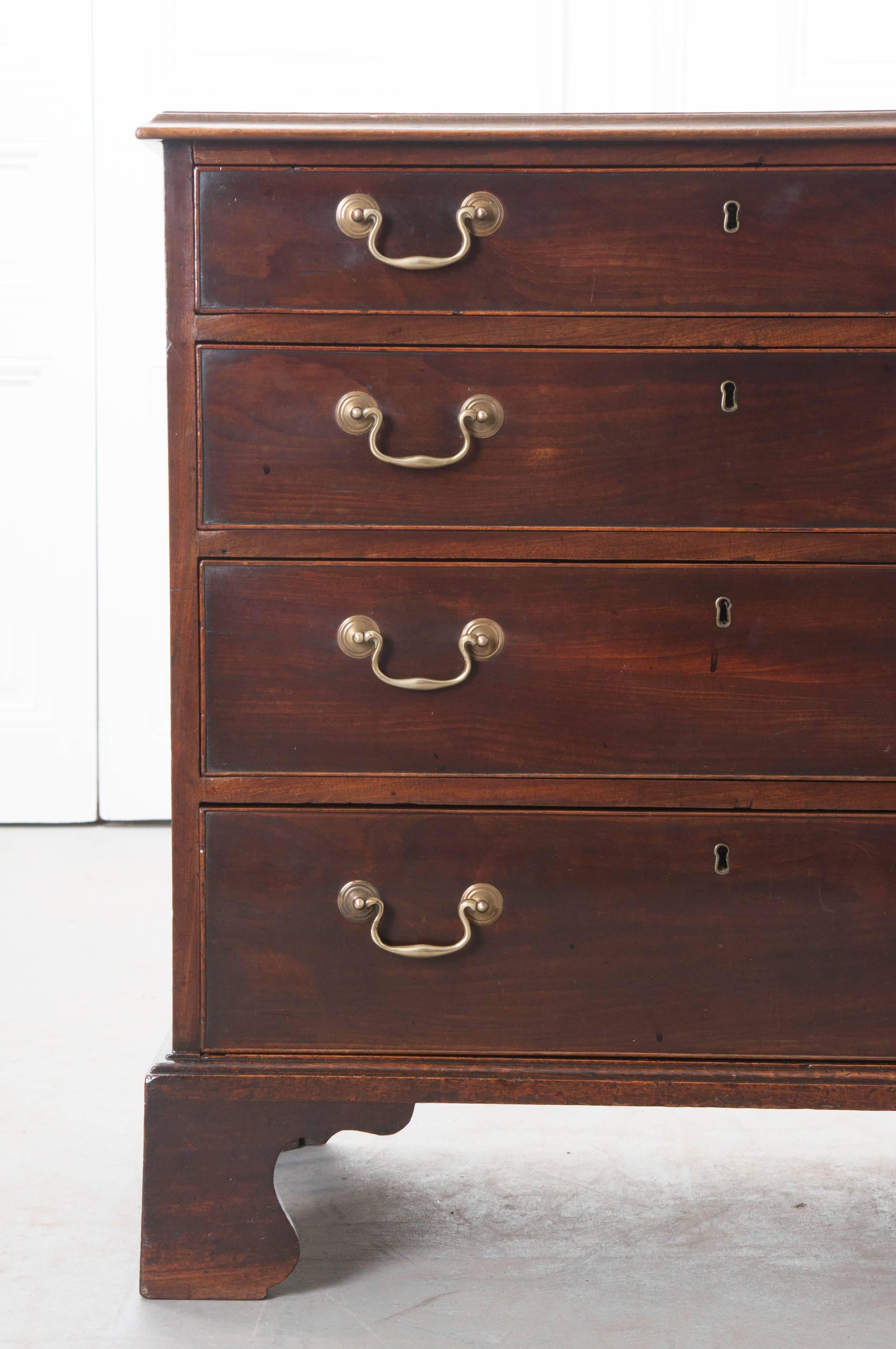 A small mahogany four drawer chest of drawers from the beginning of the 19th century, England. The four graduated drawers each have two shaped brass bail handles and inset brass escutcheons. The handsome mahogany is rich, with deep, dark tones and