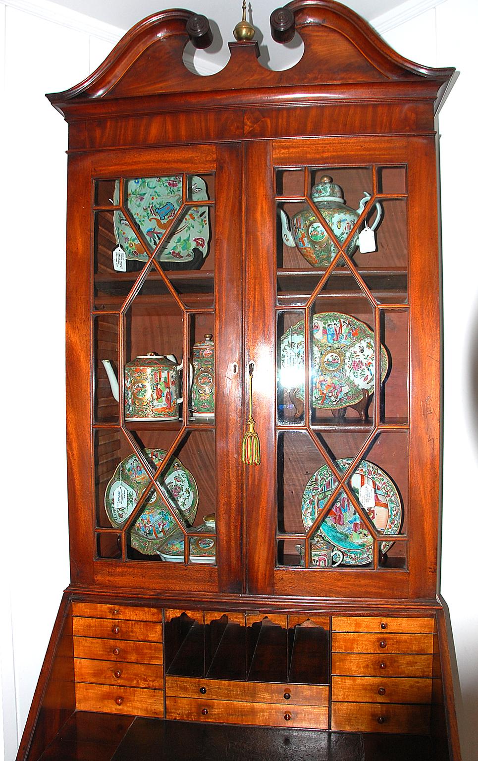 English Georgian Hepplewhite mahogany bureau bookcase with swans neck pediment above astragal glazed doors enclosing three adjustable shelves. The fall front desk opens to reveal an old black leather writing surface, satinwood banks of small drawers