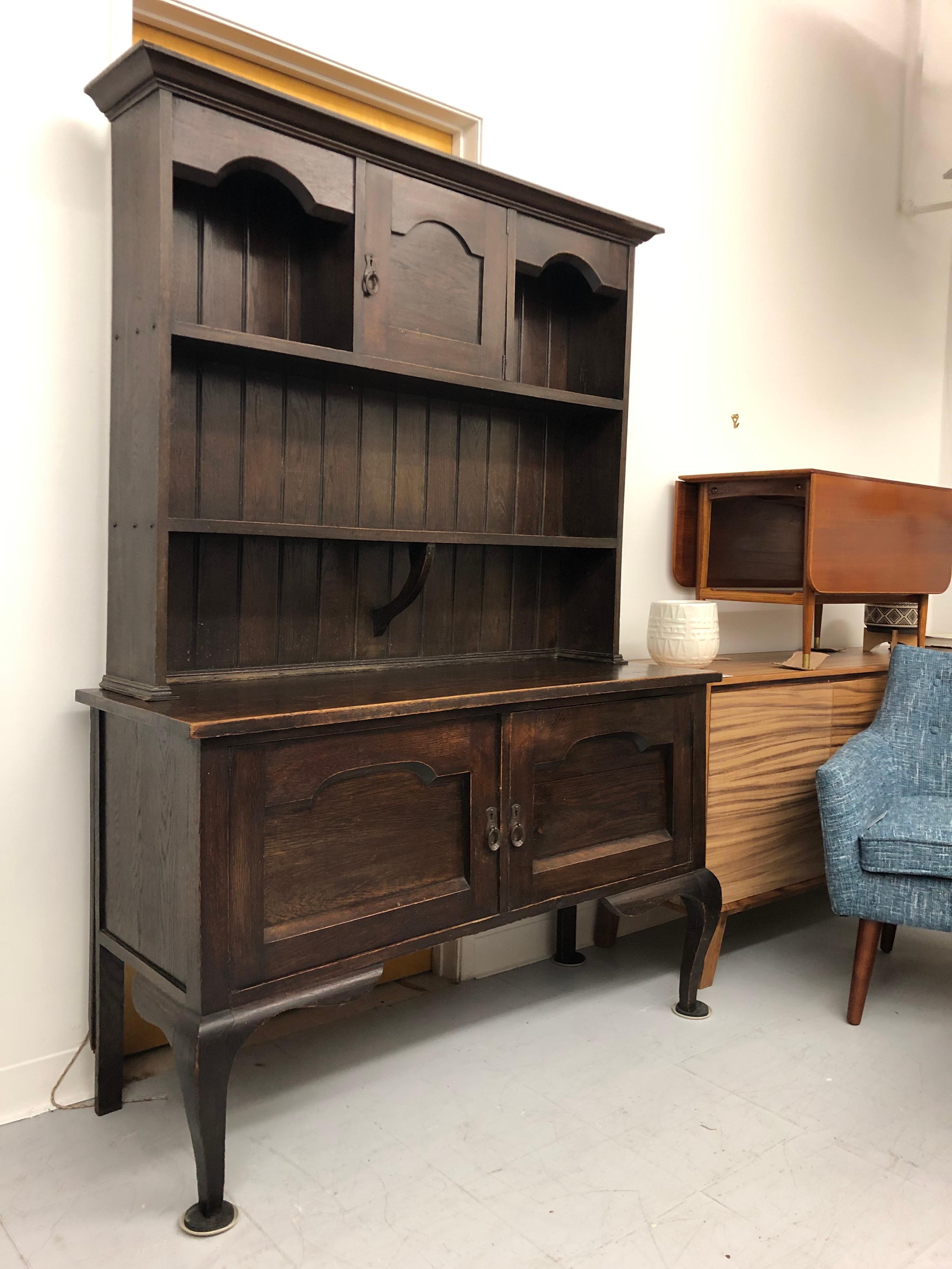 A late 18th century two-part English oak Welsh server or buffet or sideboard with an exceptional patina from the Georgian period. The upper section has three shelves and a central cupboard door. The lower section has a french frame style design and