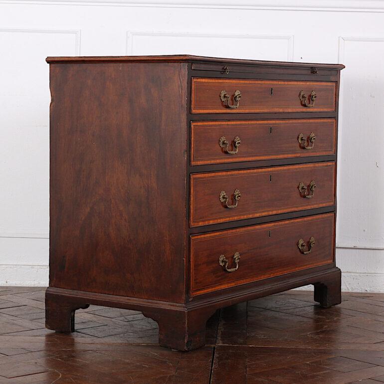 English Georgian mahogany chest of drawers, the top and drawer fronts with inlay and banding in exotic woods. Four graduated drawers with brass swan neck pulls, and with brushing slide fitted above, the whole raised on shaped bracket feet. 

 
