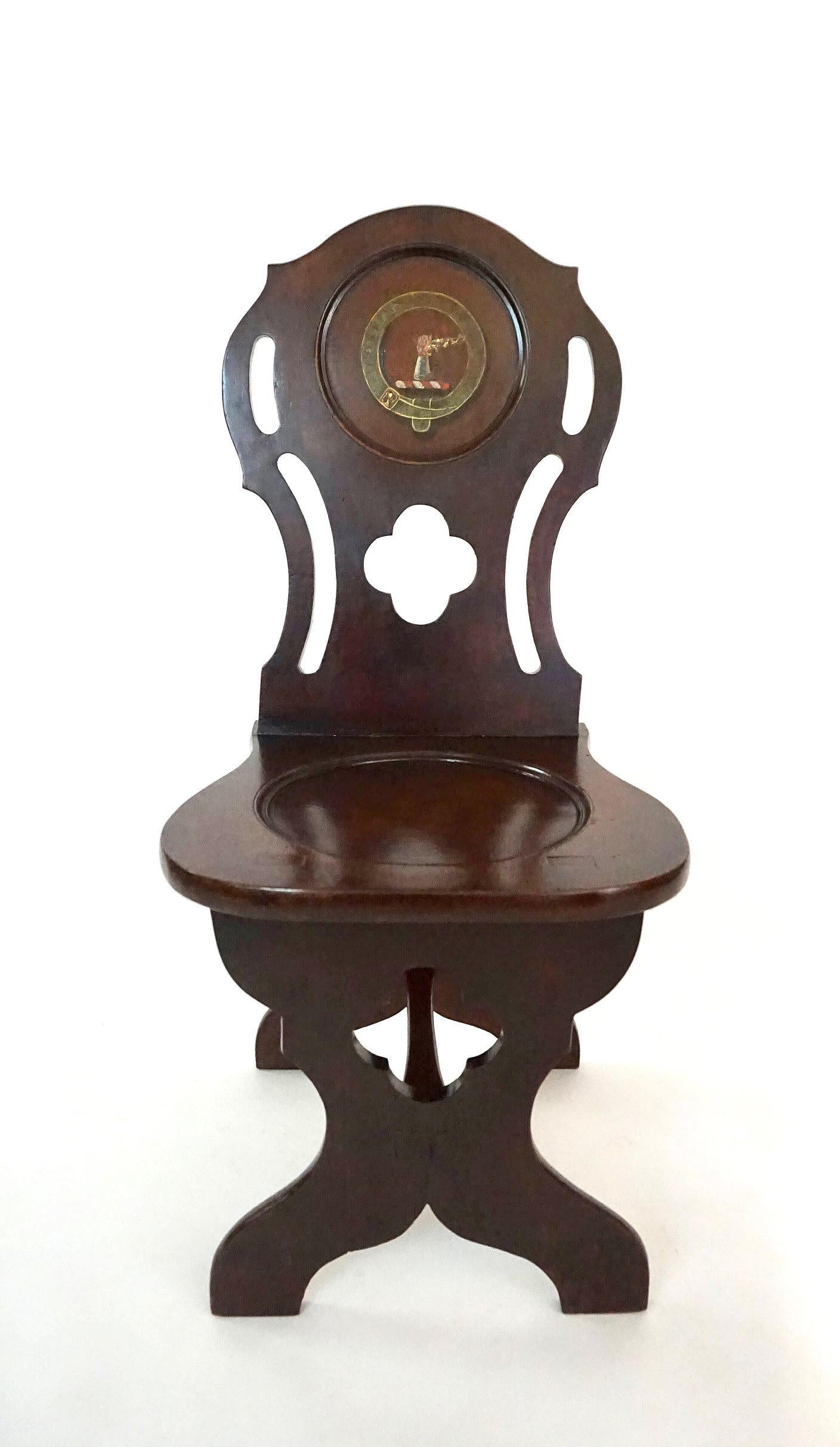 A late English George II, early George III period hall seat of 'sgabello' form having carved mahogany frame, the lancet and quatrefoil pierced shaped back with painted armorial of gauntleted forearm clenching short sword and Latin inscription in