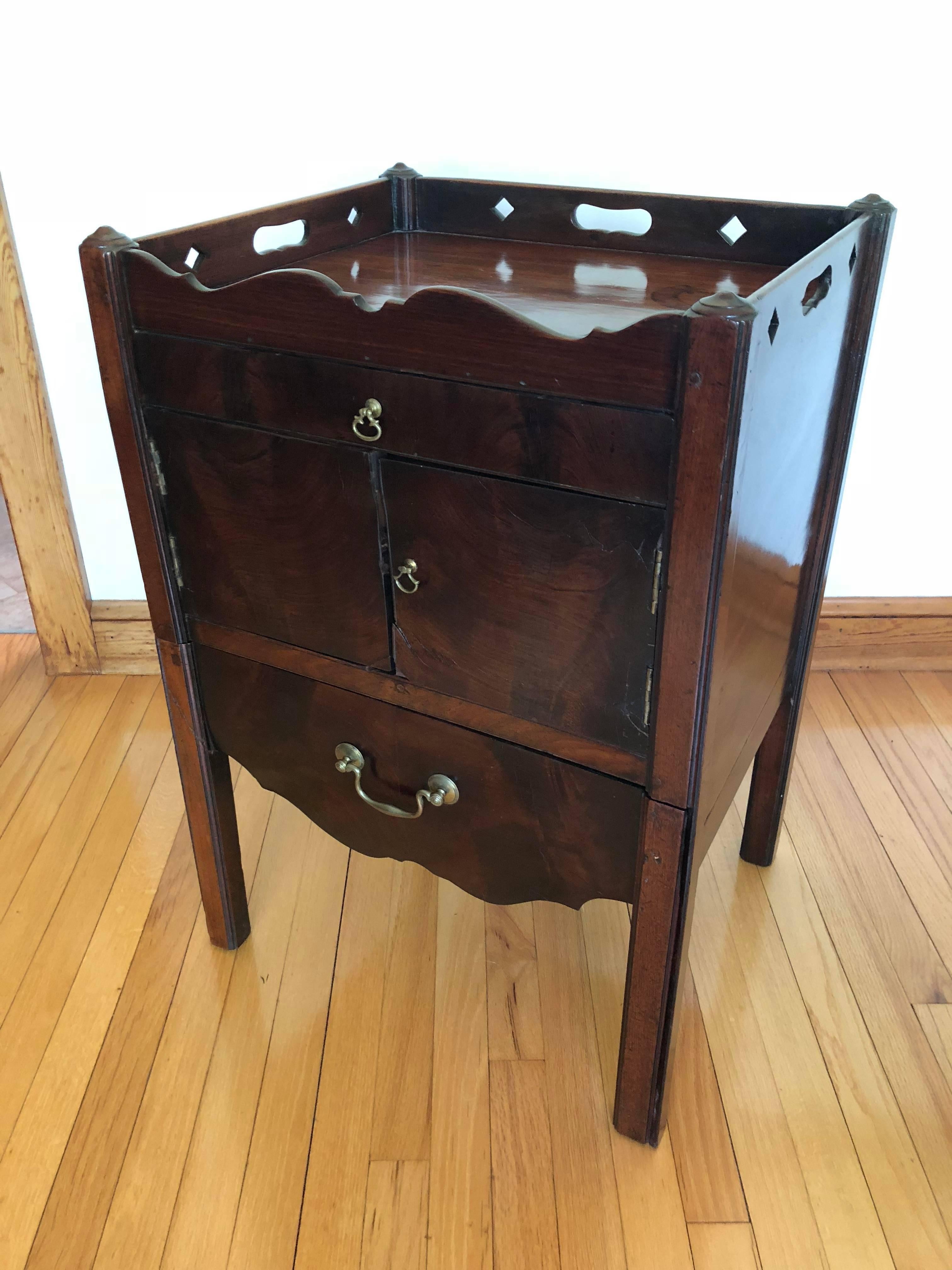 English Georgian mahogany bedside nightstand or commode. Scalloped and pierced handled tray top above single drawer and double doors. Pull-out pot drawer below.