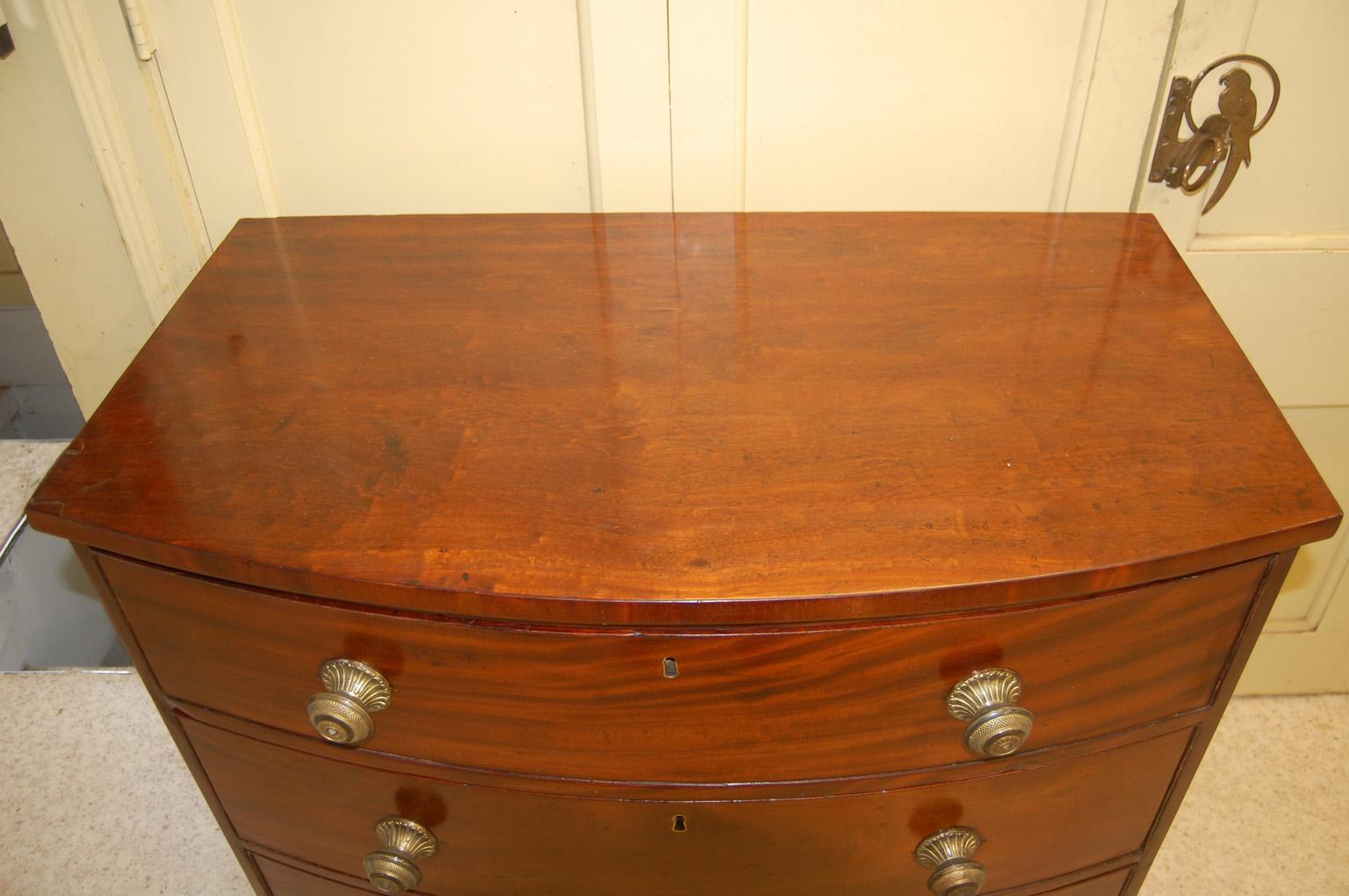  English Georgian mahogany bowfront chest of three drawers with French feet and diamond shaped stringing on a boxwood ground.  The skirt is shaped on all three sides and is set off by the inlaid stringing with a diamond motif.  The drawers have