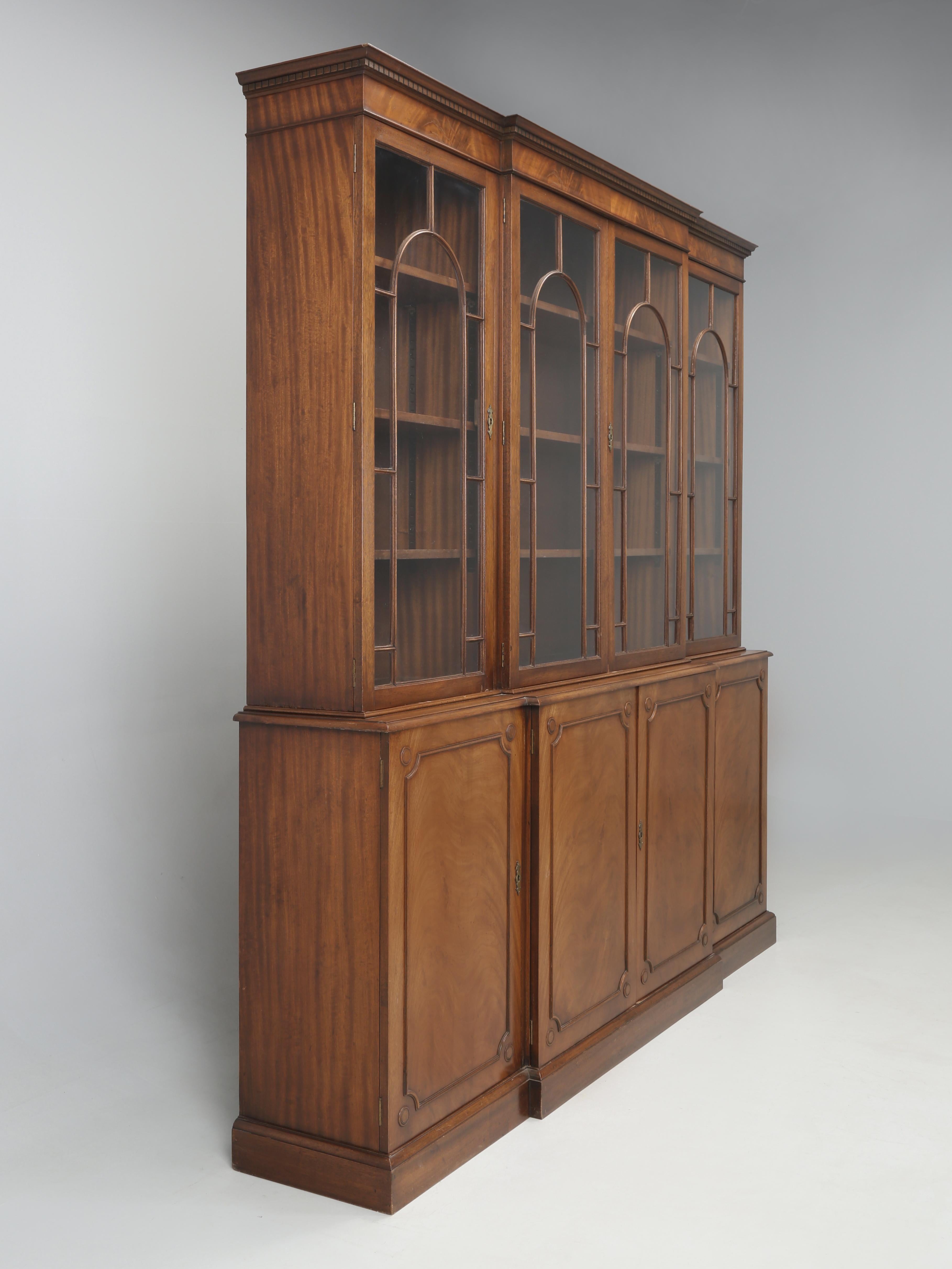 Vintage English Georgian Style Breakfront Mahogany Bookcase or China Cabinet with four beautiful and unusual arch glass doors. The Georgian Style English Mahogany Bookcase appears to be in completely original condition and is very presentable as is,
