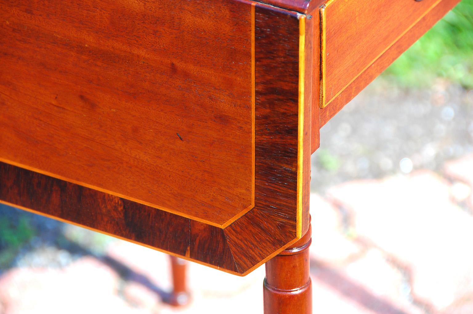 English George III mahogany dropleaf pembroke or side table with elegant turned tapered legs, rosewood crossbanding, satinwood stringing and one drawer. This is an unusual size for a pembroke table, being smaller than most, but quite versatile. It