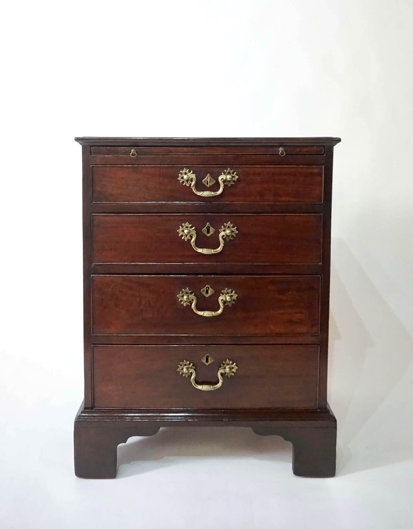 Une belle commode de célibataire en acajou de style Chippendale, de forme peu commune, le dessus à bord mouluré au-dessus d'une glissière de brossage et de quatre tiroirs gradués, tous avec des ferrures en laiton d'origine, les écussons des clés