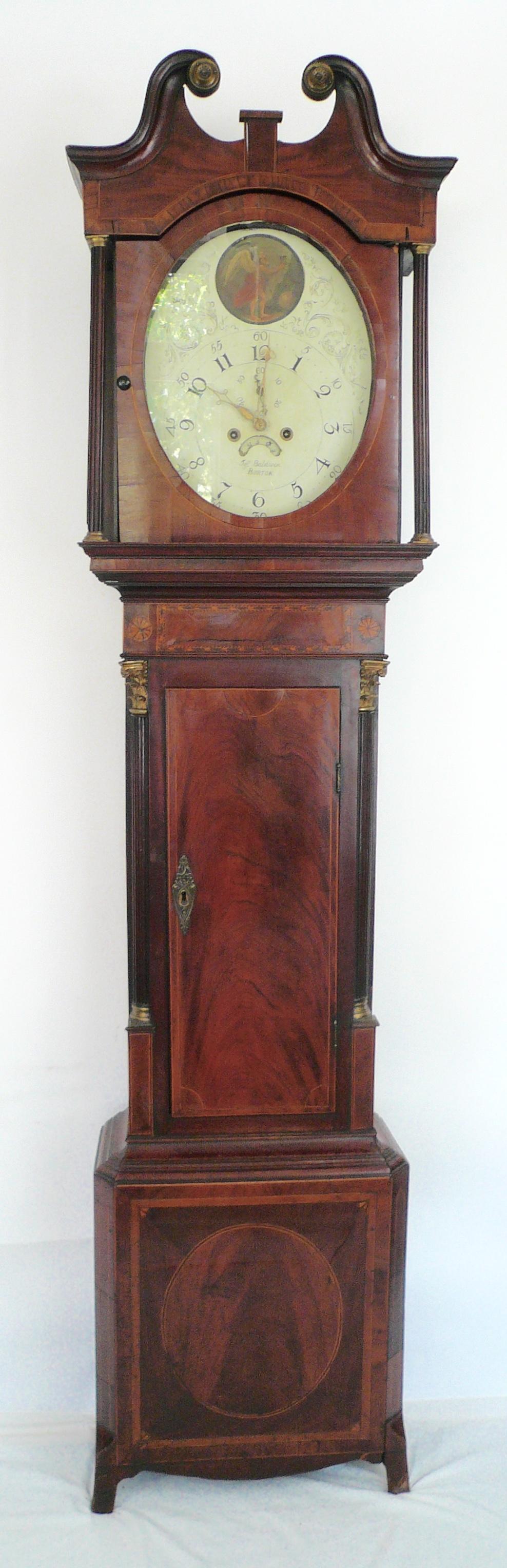 This beautiful inlay mahogany clock features a hand painted oval dial, broken arch pediment, and fluted columns.