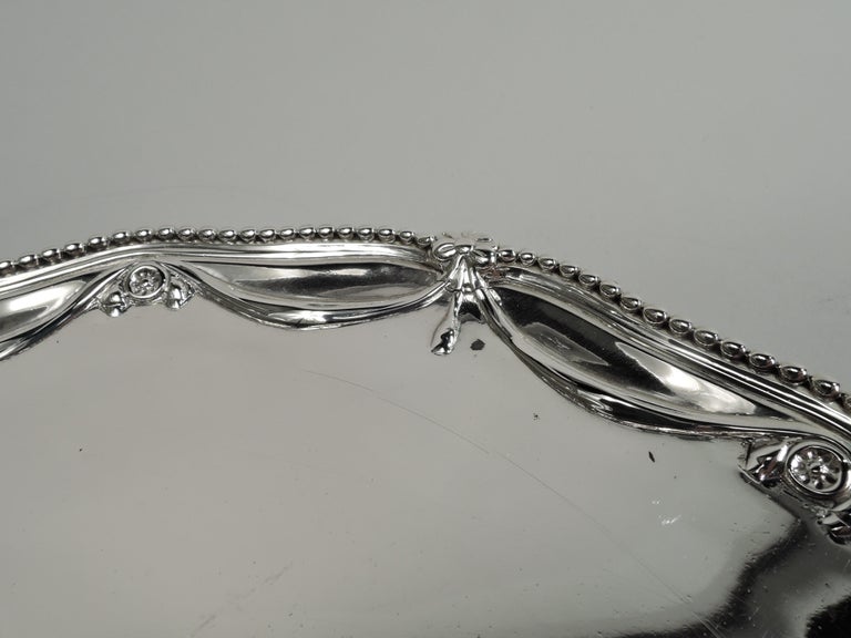 George III sterling silver salver. Made by Richard Rugg in London in 1775. Serpentine with beaded rim and chased pendant swags. Rests on 3 claw-and-ball feet. Fully marked. Weight: 13 troy ounces.