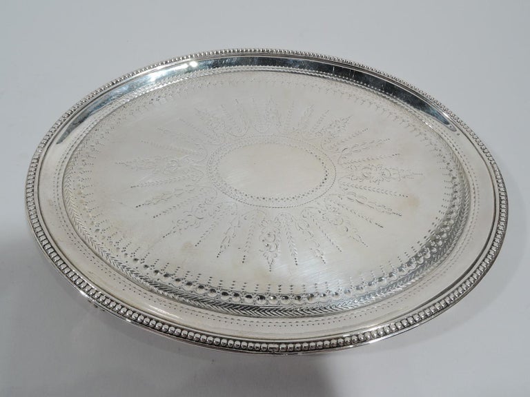 George III sterling silver salver. Made by Elizabeth Jones in London in 1784. Each: Oval with beaded rim and 4 beaded triangular supports. Neoclassical ornament including large central patera (vacant) engraved on well. Fully marked. Weight: 12 troy