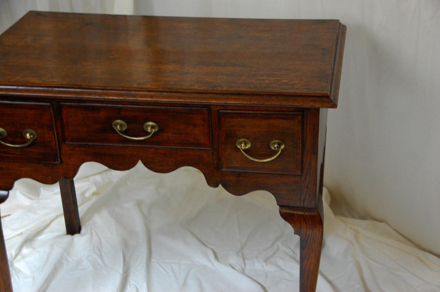 English Georgian oak lowboy with three mahogany crossbanded drawers, cabriole front legs and shaped skirt to front and sides. The drawers were rebuilt using the original drawer fronts but new oak for the rest of the drawers, also new drawer slides,