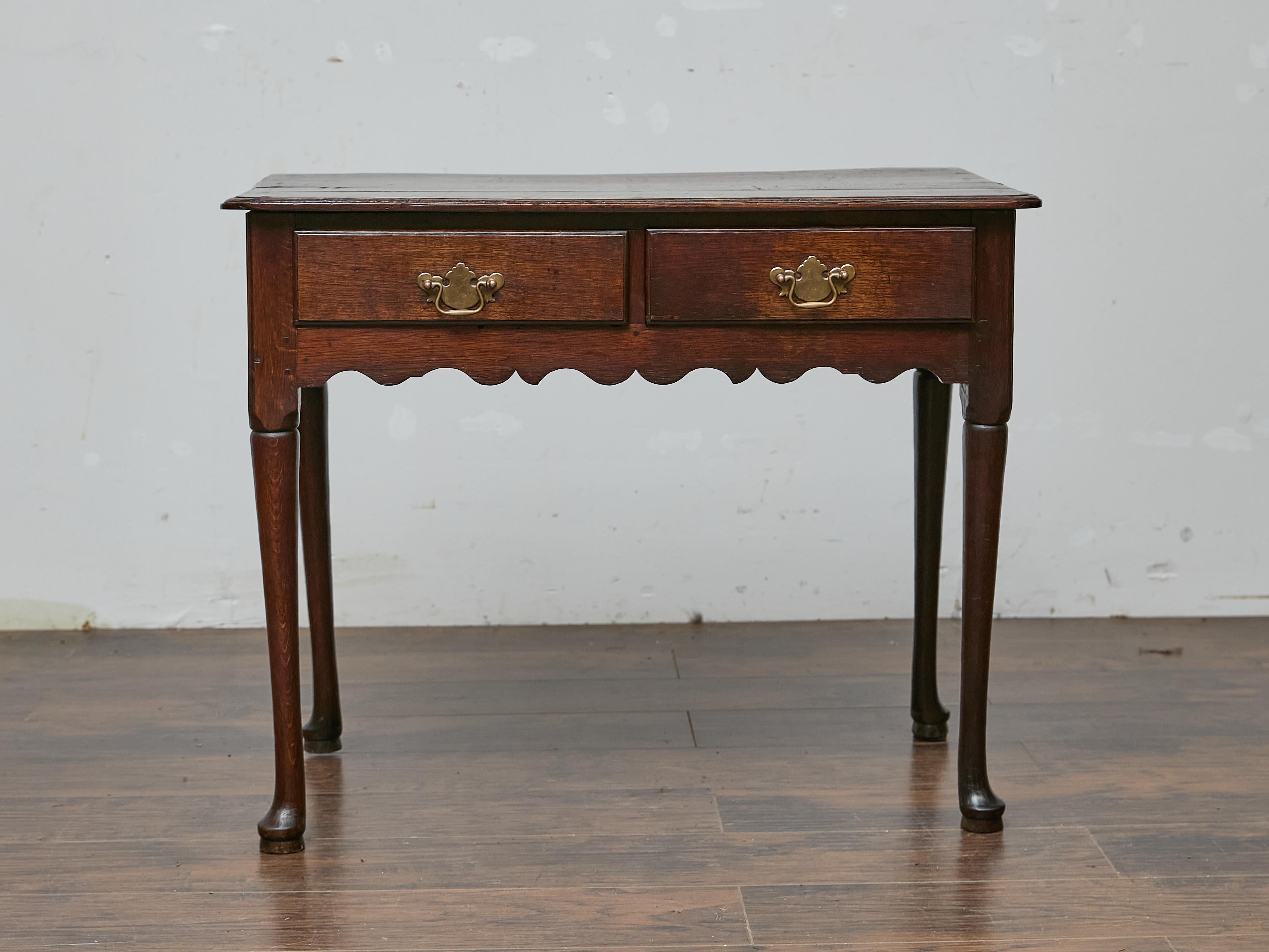 Cette table en chêne anglais, vers 1800, est un bel exemple de l'artisanat du début du XIXe siècle, avec une finition riche et sombre qui renforce son attrait intemporel. Dotée d'un tablier joliment festonné et de pieds élancés avec des pieds pad,