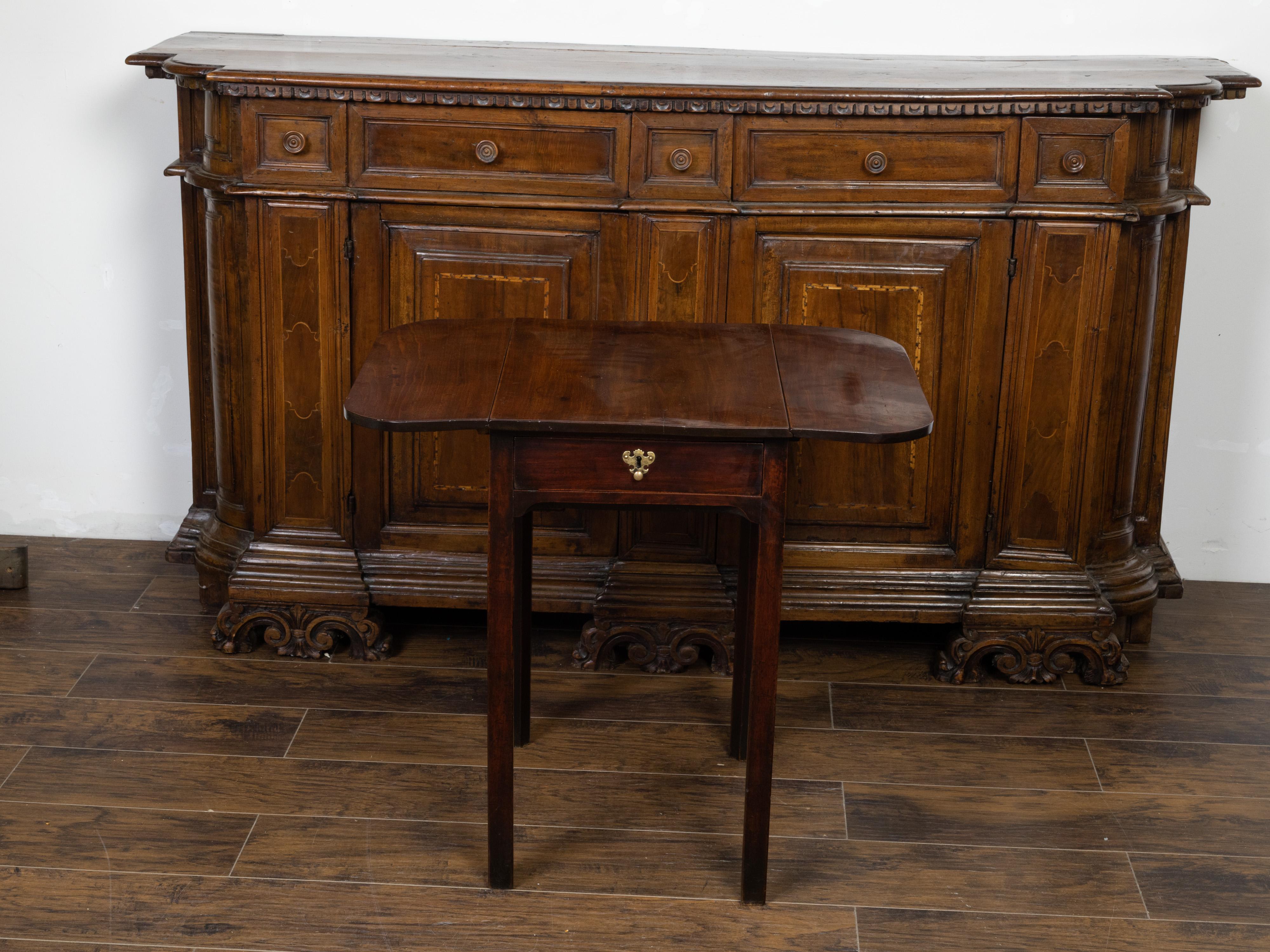 An English Georgian period mahogany pembroke table from the early 19th century, with single drawer and Chippendale style hardware. Created in England during the early years of the 19th century, this mahogany pembroke table features a rectangular top