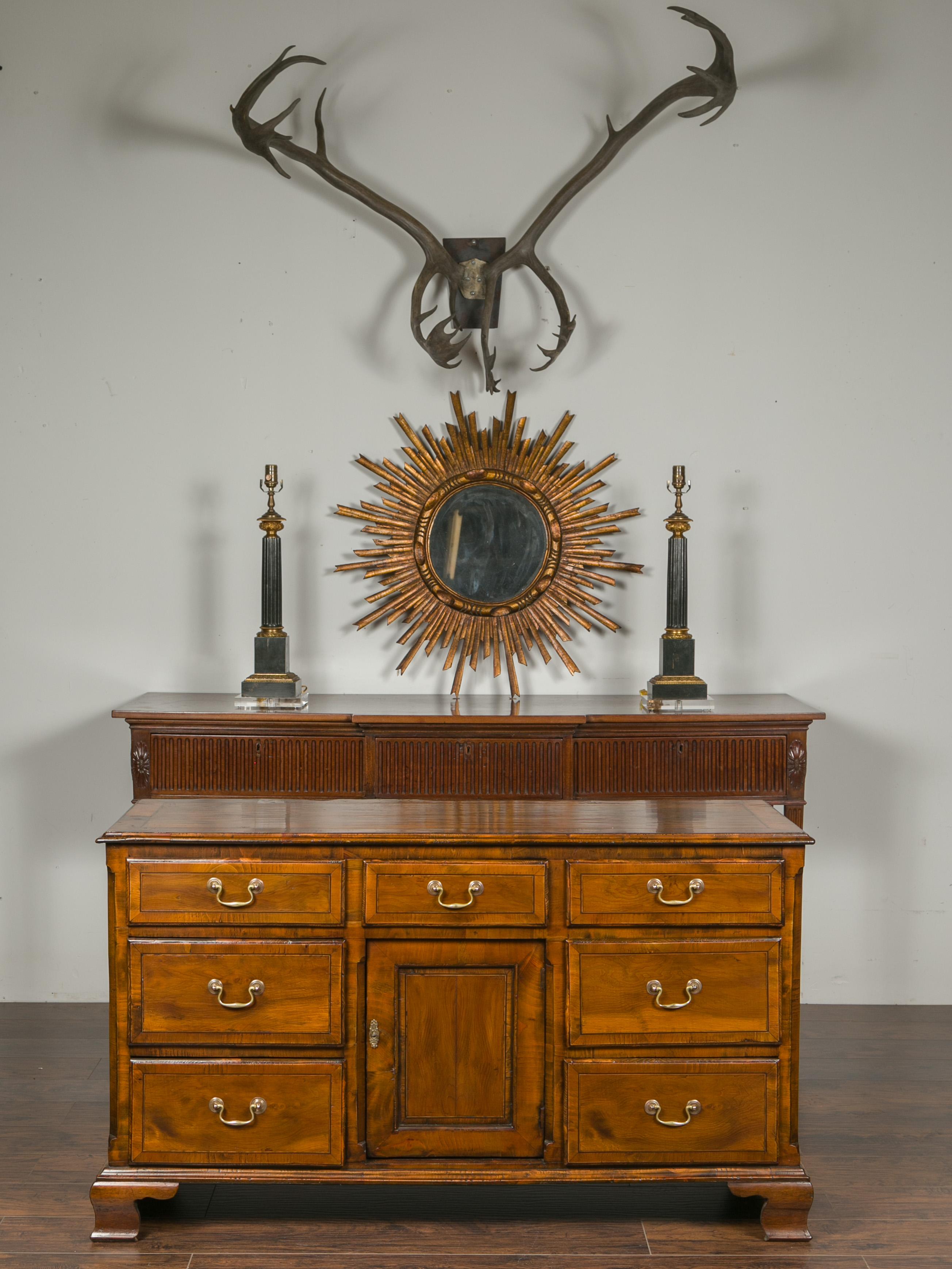 An English Georgian period oak dresser base / server from the early 19th century, with seven drawers, single door and ogee bracket feet. Created in England during the early years of the 19th century, this long oak server features a rectangular top