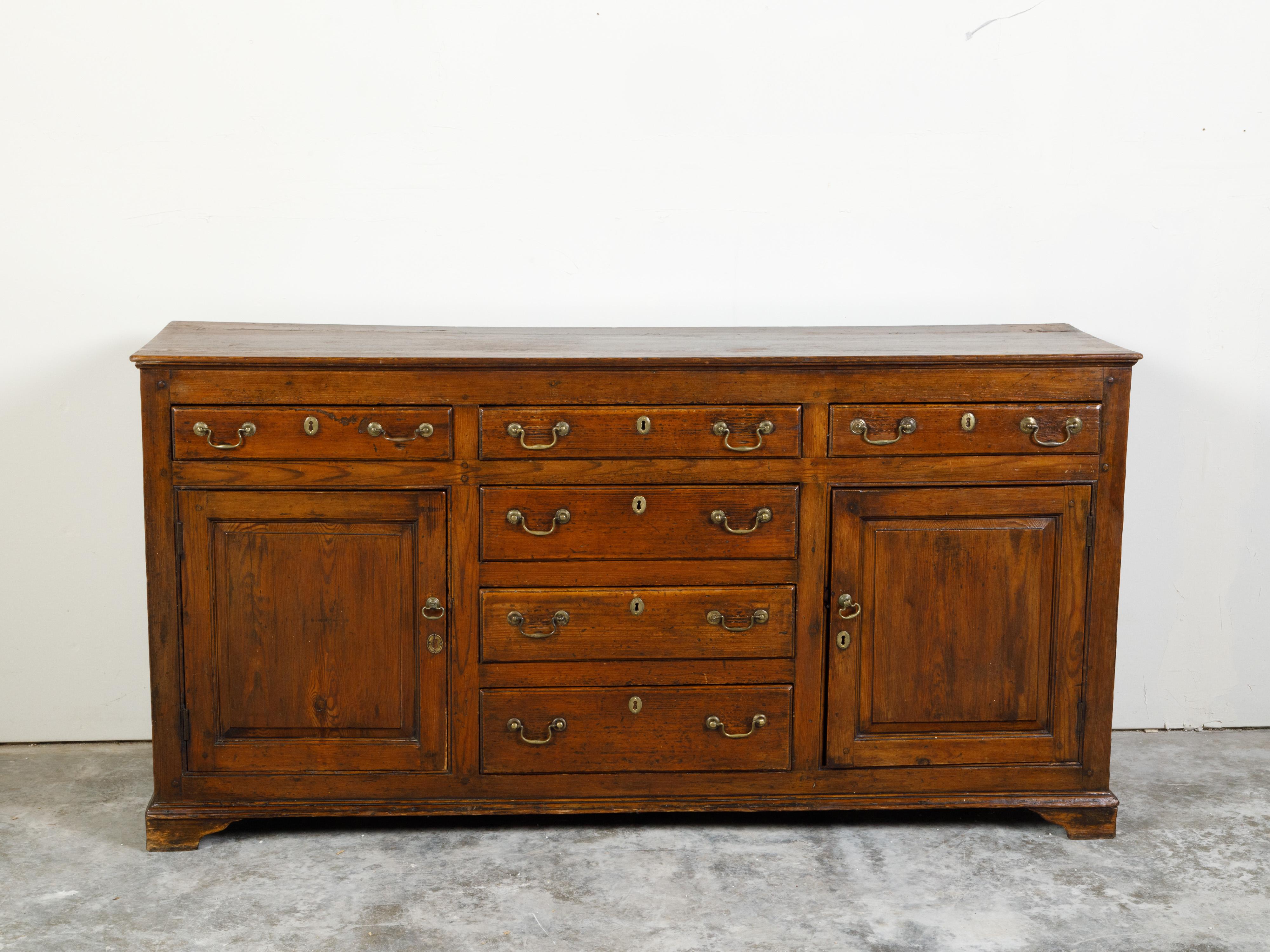 An English Georgian period oak dresser base from the early 19th century, with six drawers, two doors and peg construction. Created in England during the early years of the 19th century, this oak dresser base features a rectangular top sitting above