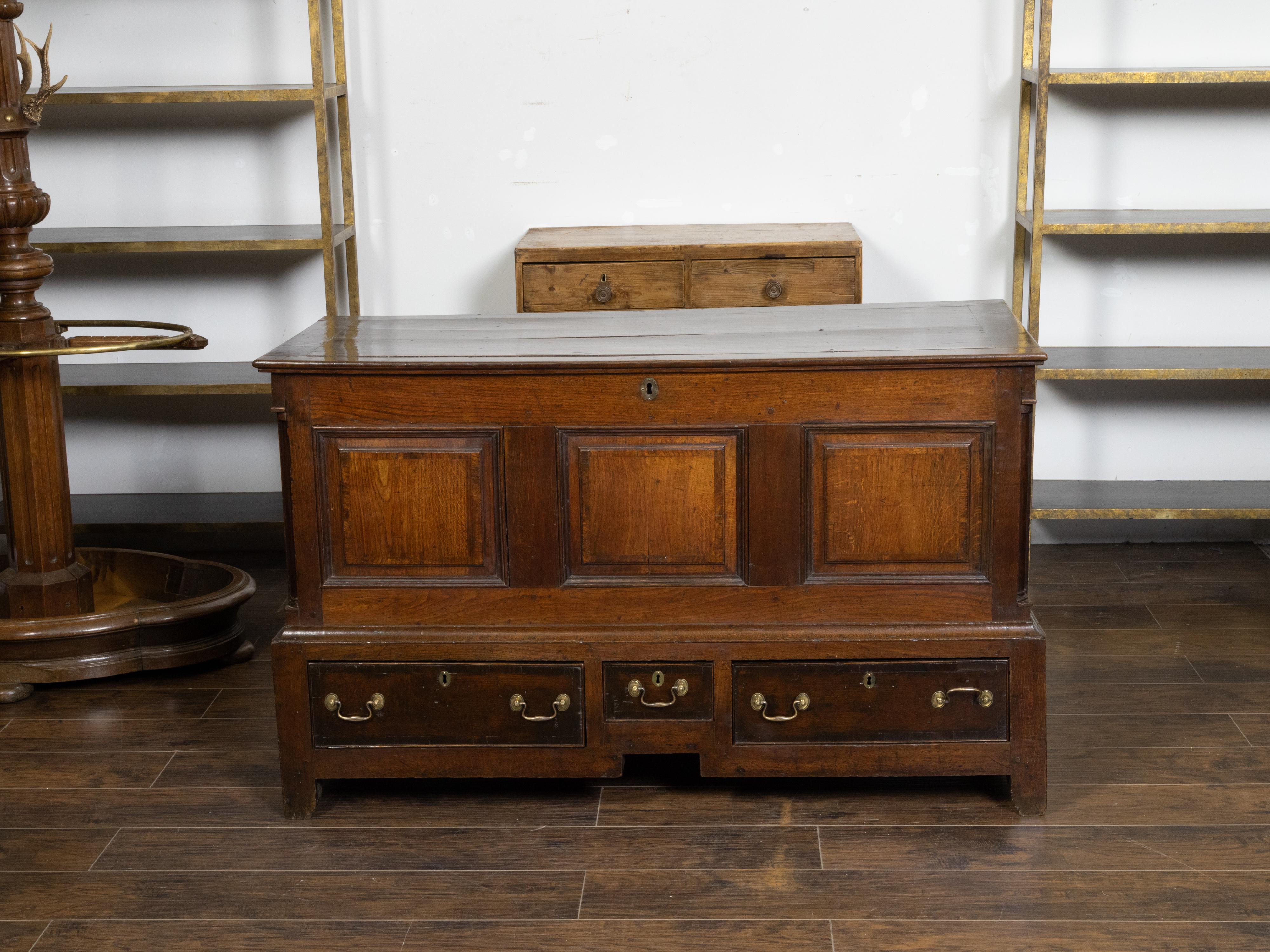 An English Georgian period oak mule chest from the early 19th century, with lift top, three drawers and brass hardware. Created in England during the Georgian period in the early years of the 19th century, this oak chest called a mule chest features