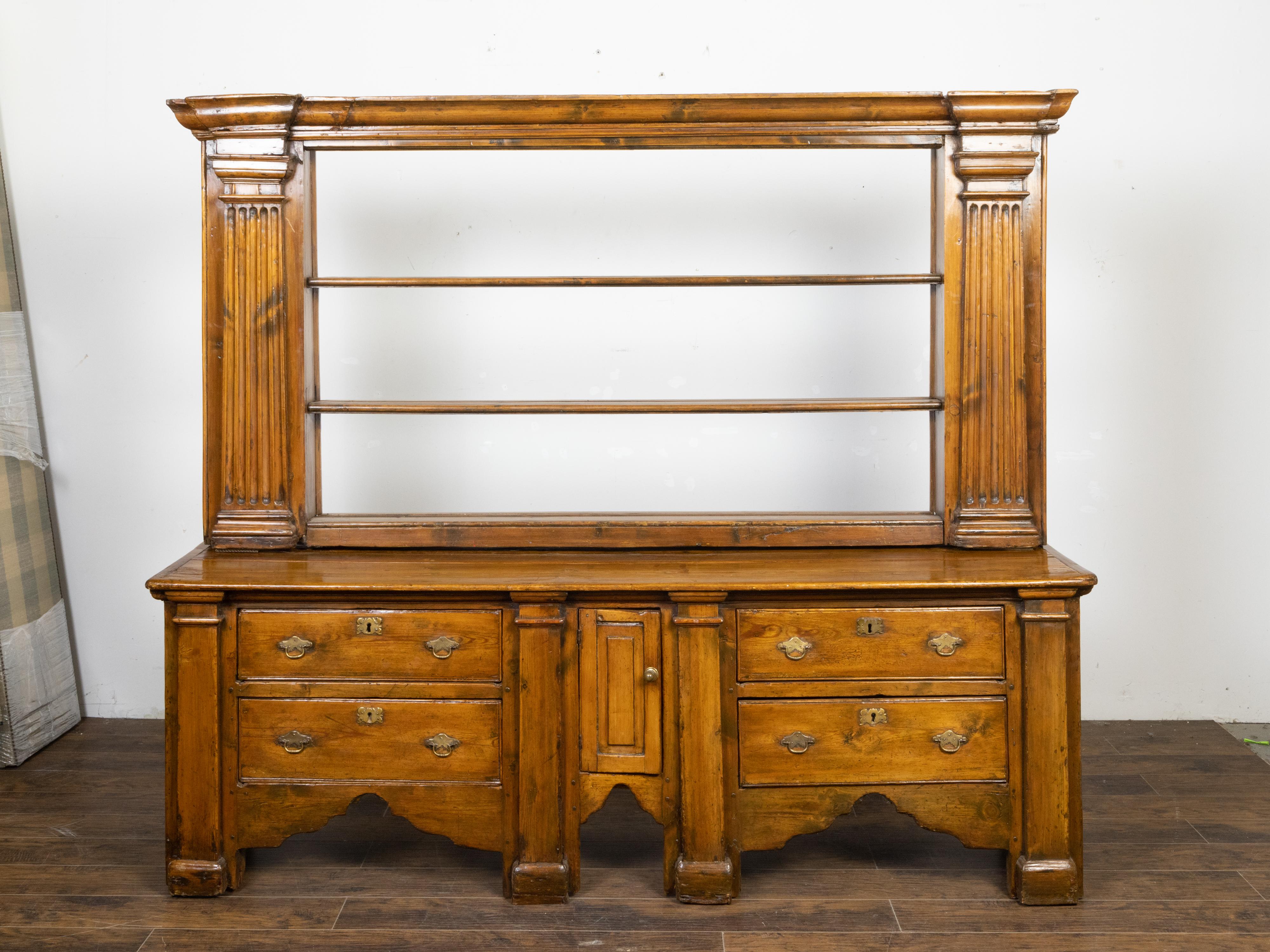 An English Georgian period pine dresser from the early 19th century, with open shelves, Doric style pilasters, petite door and four drawers. Created in England during the Georgian period in the early years of the 19th century, this elegant pine