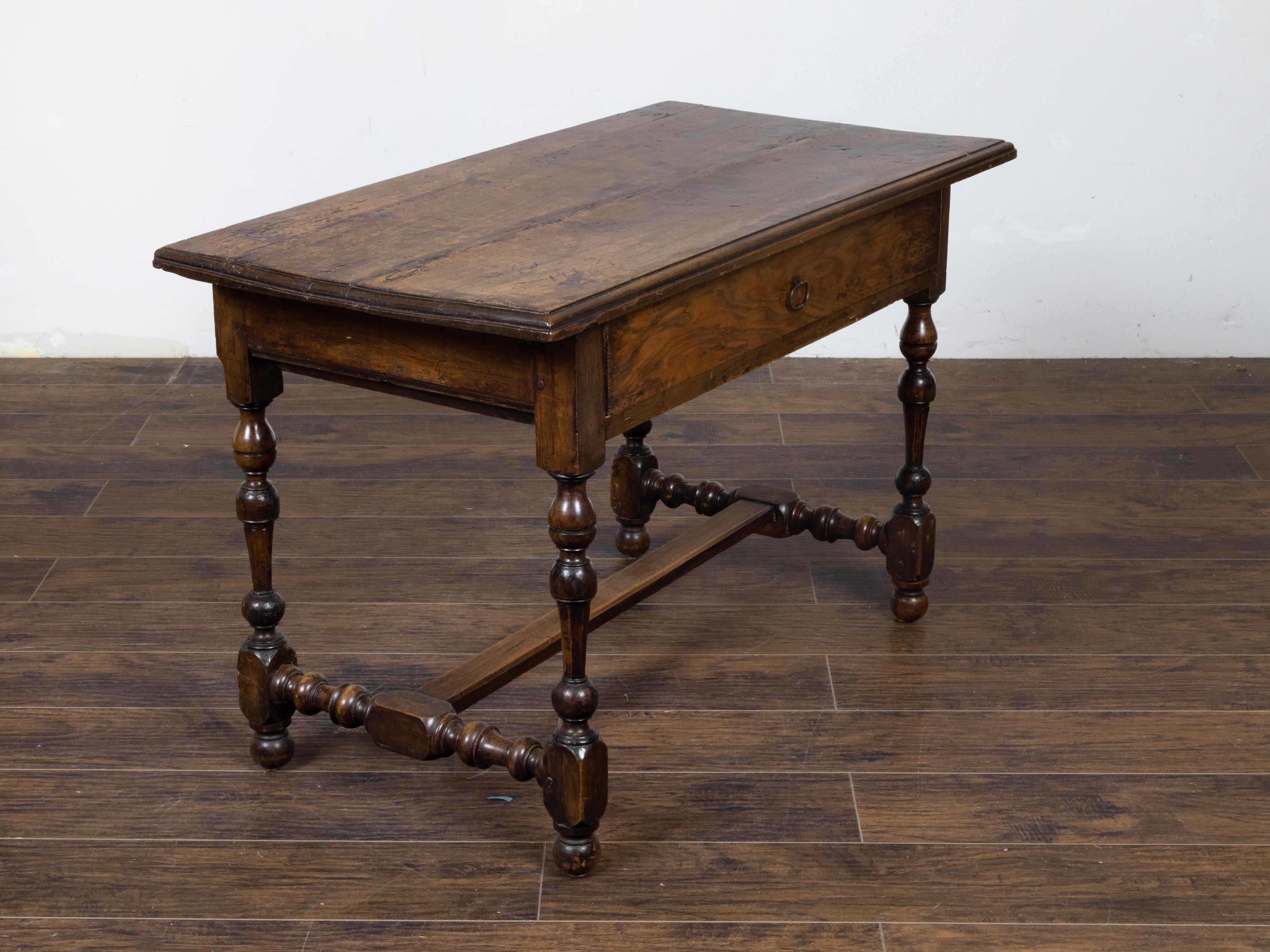 An English Georgian period walnut table circa 1800 with rectangular top, beveled edges, single drawer, slender turned baluster legs on ball feet and H-Form cross stretcher. Radiating an undeniable charm, this English Georgian period walnut table,