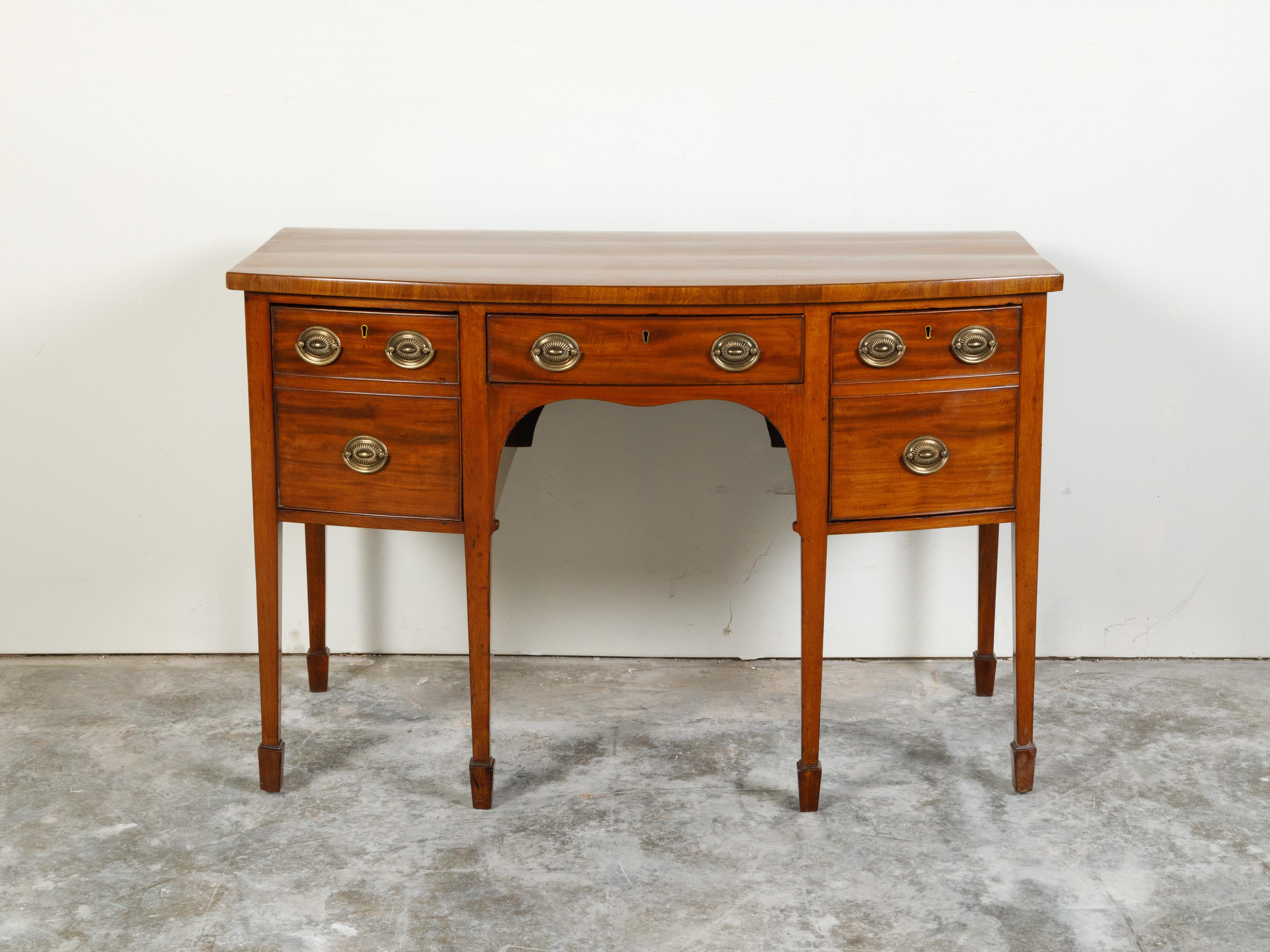 An English Georgian period mahogany sideboard from the early 19th century, with five drawers, tapered legs and spade feet. Created in England during the first quarter of the 19th century, this mahogany sideboard features a rectangular bow front top