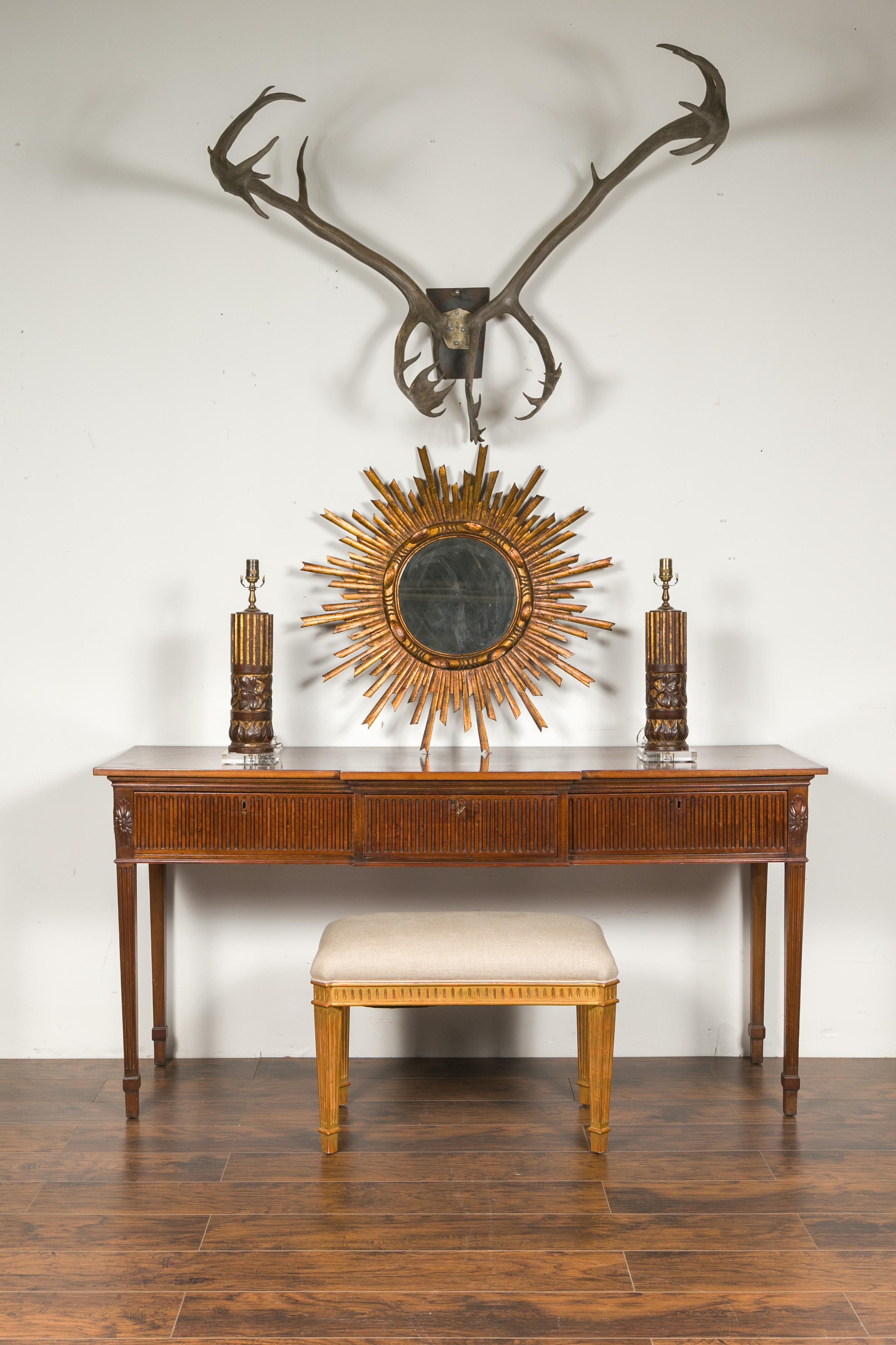 An English Georgian period mahogany breakfront sideboard from the early 19th century, with fluted motifs, tapered legs and three drawers. Born in England during the first quarter of the 19th century, this Georgian mahogany sideboard features a