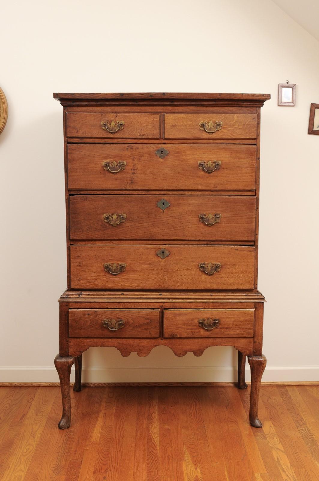 An English Georgian period oak highboy from the early 19th century, with seven drawers and cabriole legs. Created in England during the first quarter of the 19th century, this handsome highboy features a simple cornice overhanging a perfectly