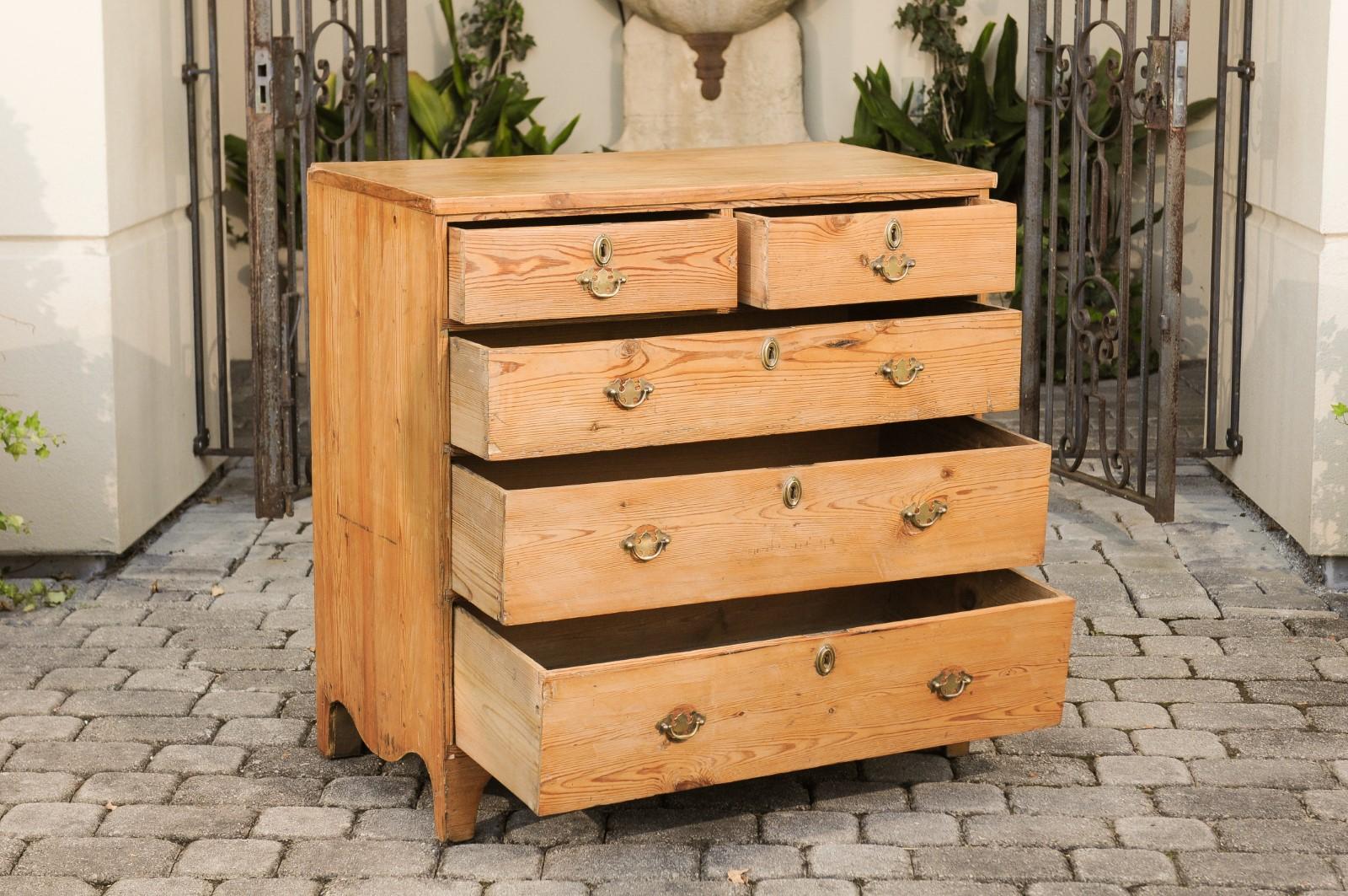 An English Georgian period pine chest-of-drawers from the early 19th century, with bracket feet. Born in England during the first quarter of the 19th century, this charming chest features a rectangular top sitting above five graduated drawers (two