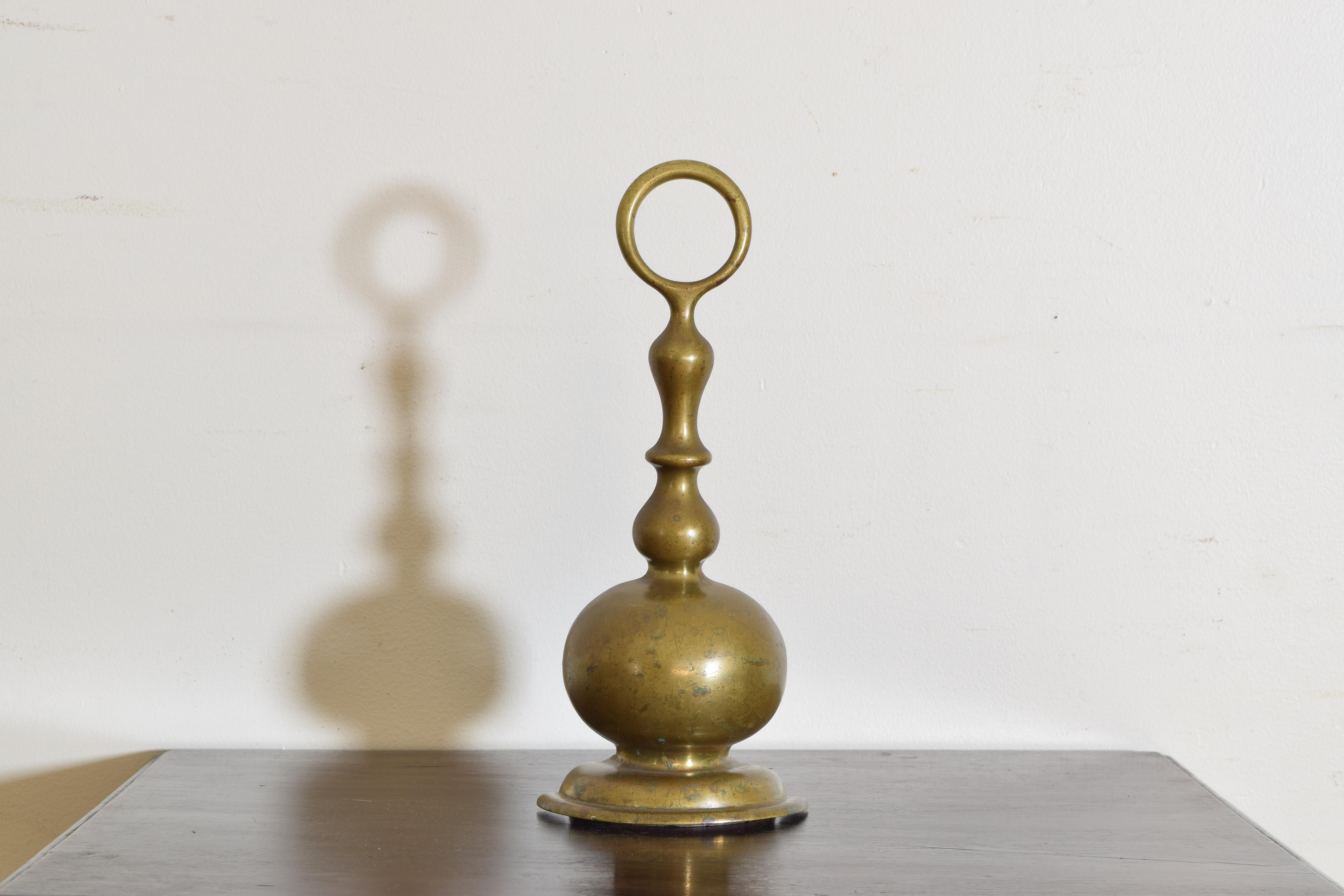 A heavy cast brass doorstop of bell shape with top ring, the reverse filled with lead as a weight.