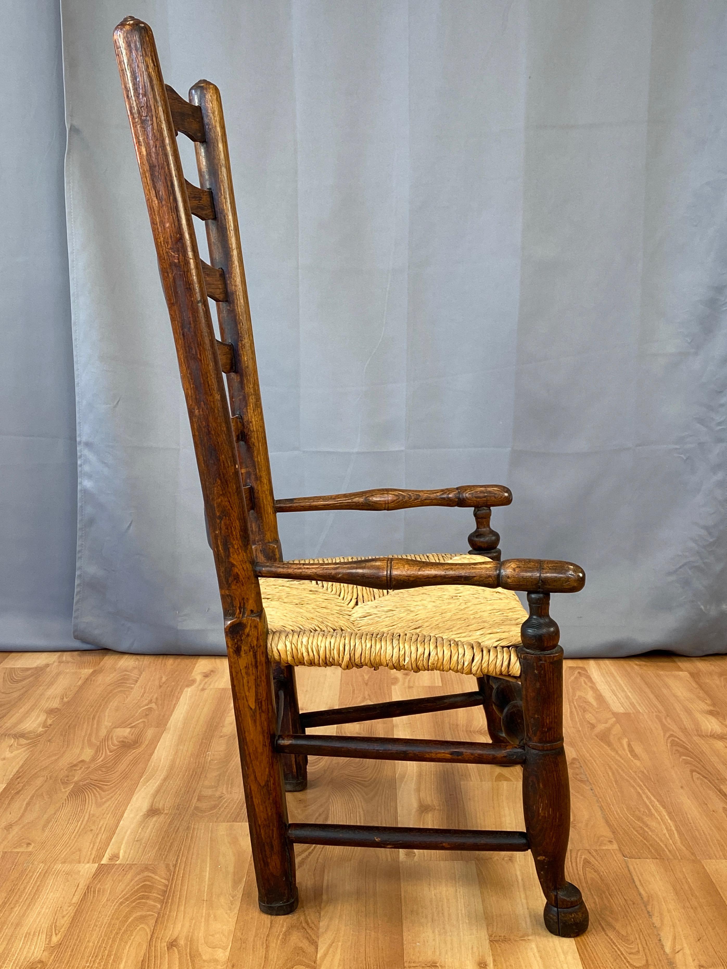 Early 19th Century English Georgian Period Elm Ladderback Fireside Armchair with Rush Seat, c. 1800 For Sale