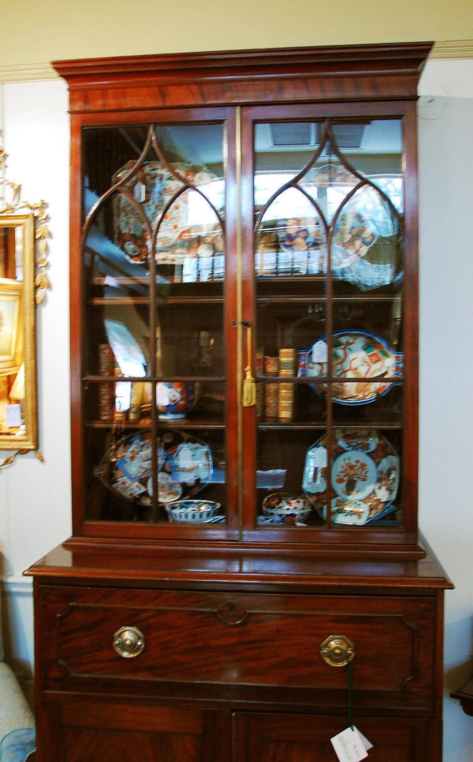 English George III Hepplewhite mahogany secretaire bookcase in two parts with secretaire drawer, cupboards and astragal molded glazed doors. The two glazed doors with arched astragal glazing enclose three adjustable molded edge shelves. The