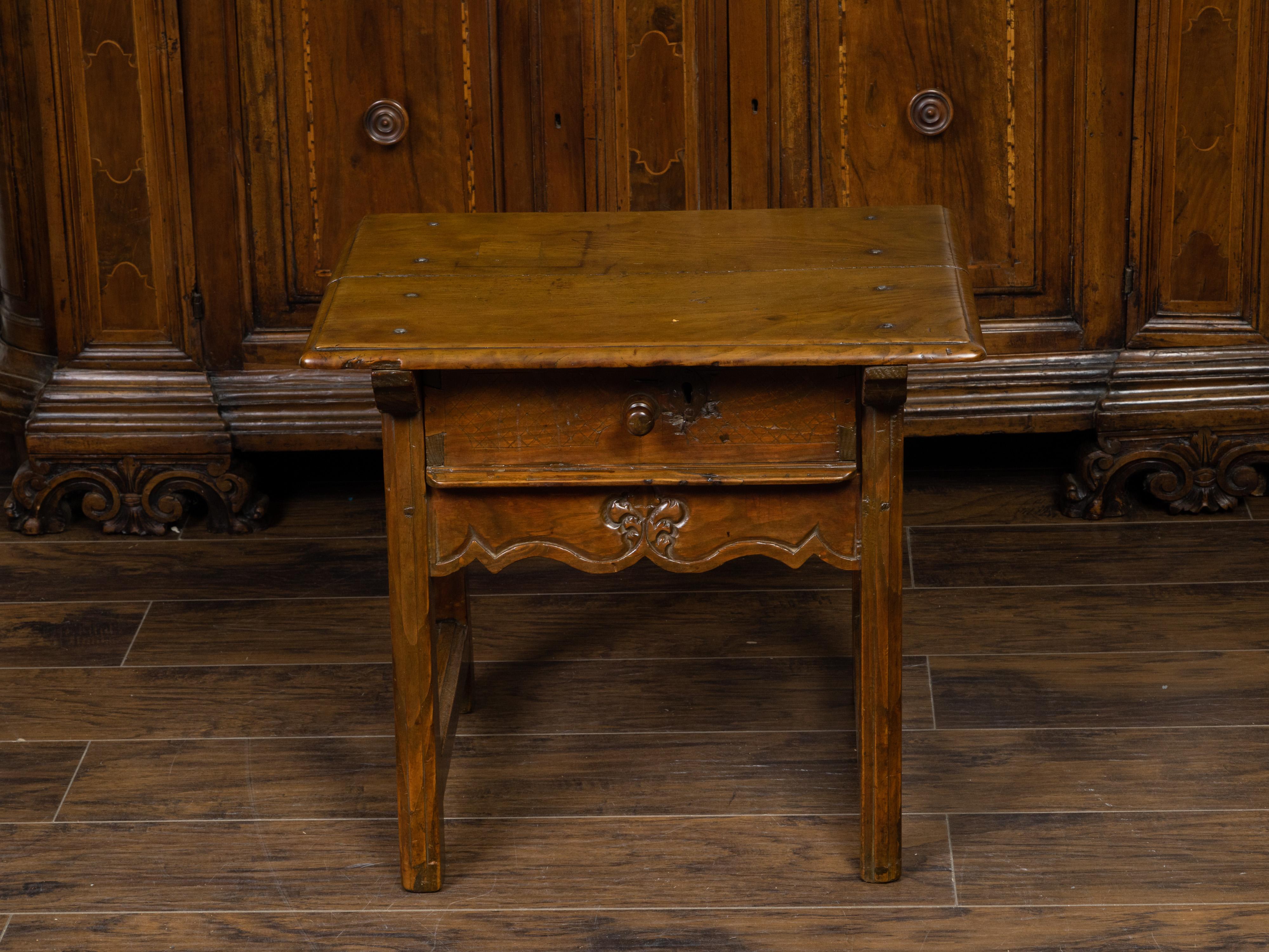 An English Georgian period oak low side table from the early 19th century, with single drawer and scalloped apron. Created in England during the early years of the 19th century, this oak side table features a rectangular planked top sitting above a