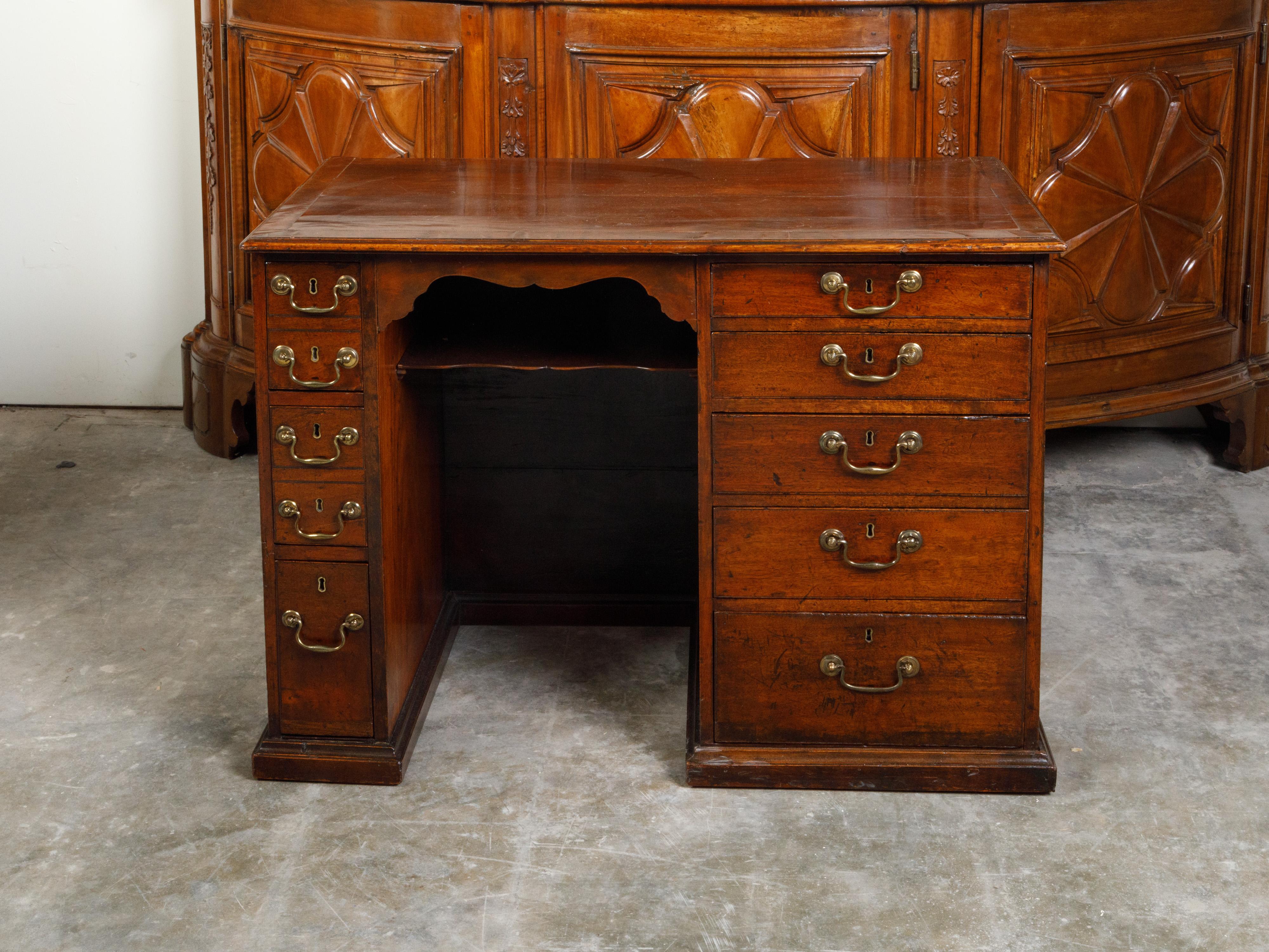 An English Georgian period mahogany desk from the 19th century, with 10 graduating drawers and brass hardware. Created in England during the Georgian period, this mahogany desk features a rectangular top sitting above 10 graduating drawers