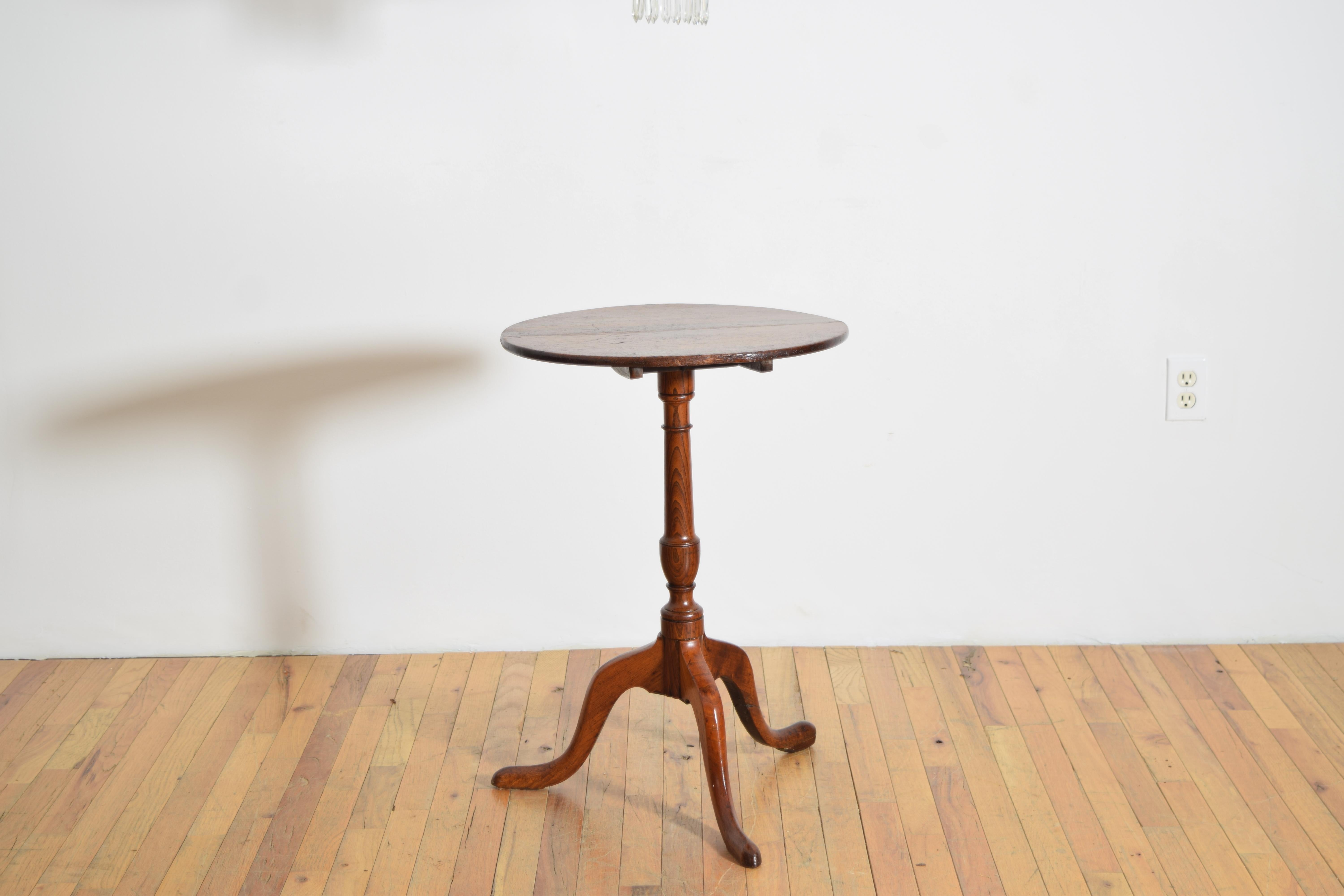 A Georgian tilt-top occasional table, circa 1780, featuring a well-patinated oak circular top over a turned elmwood pedestal and tripod base.  Original iron latch mechanism intact.