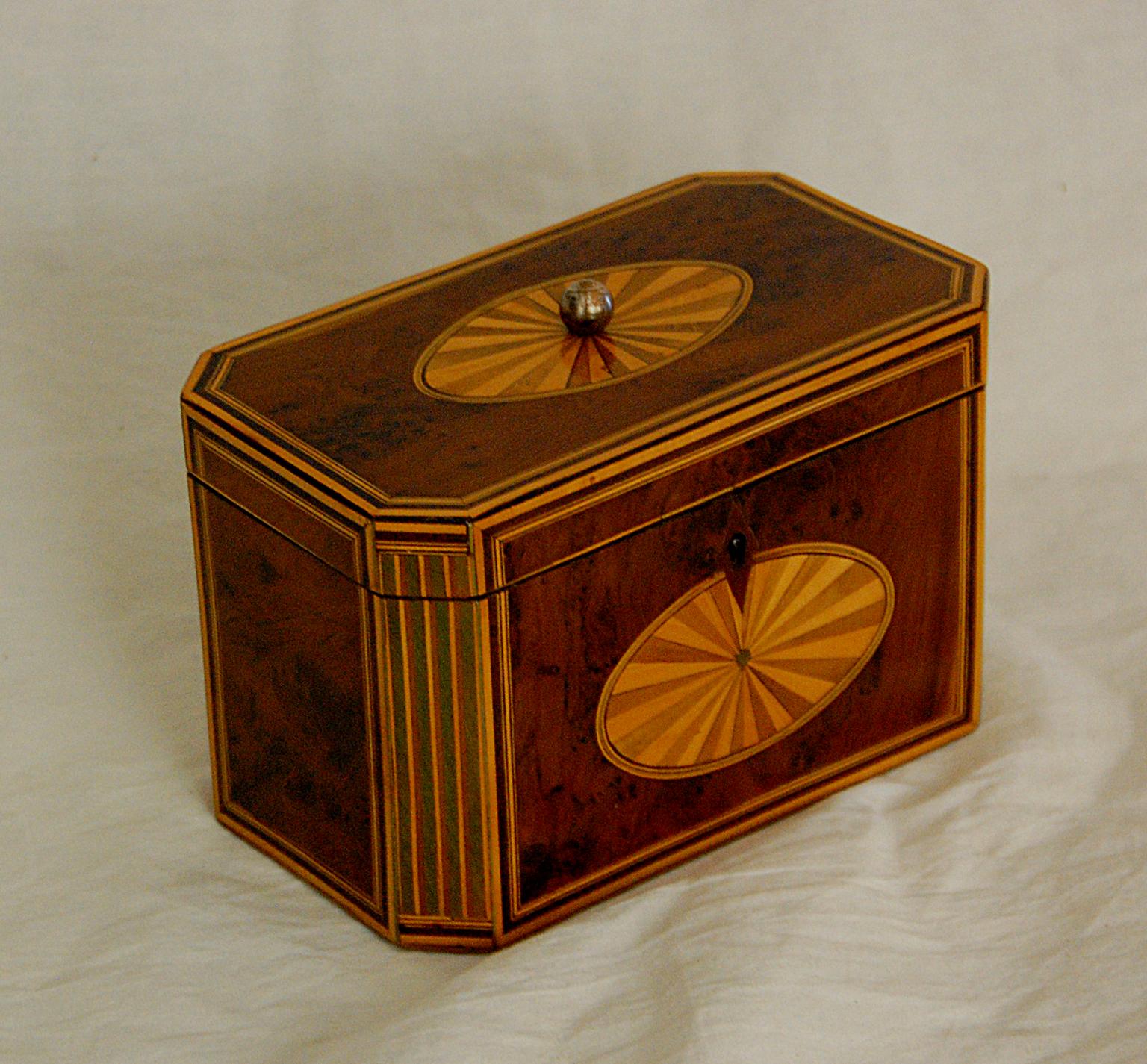 English Georgian 18th century yew wood octagonal tea caddy inlaid with fan and column motifs in satinwood, sycamore and boxwood. Multiple lines of stringing in satinwood, boxood and rosewood frame each panel of the tea caddy. The two interior tea