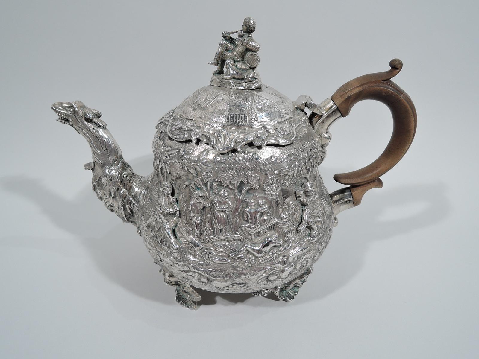 George IV sterling silver tea set. Made by Edward Farrell in London in 1822-1823. This set comprises 3 pieces: Teapot, creamer, and sugar.

Teapot has squat baluster body. Cover hinged, domed, and overhanging. S-scroll spout in form of shaggy,