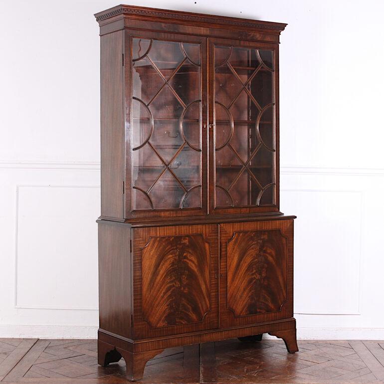 English Georgian style mahogany bookcase, the top with a pair of astragal-glazed doors opening to adjustable shelves, the cabinet base with flame mahogany veneered doors and standing on splayed bracket feet. Mid-20th century. Piece separates into