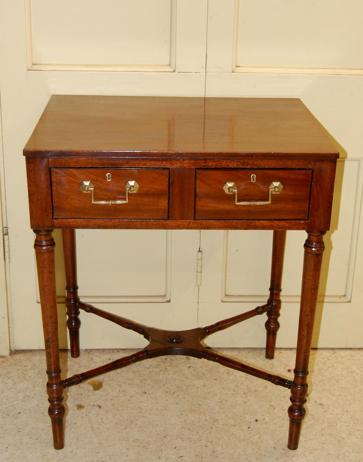   English Georgian Sheraton mahogany two drawer side table.  This handsome table is finished on all sides, has tapered turned legs and an elegant turned cross stretcher.  There is ebony line inlay to the edges of the two drawers.  Circa 1800. 